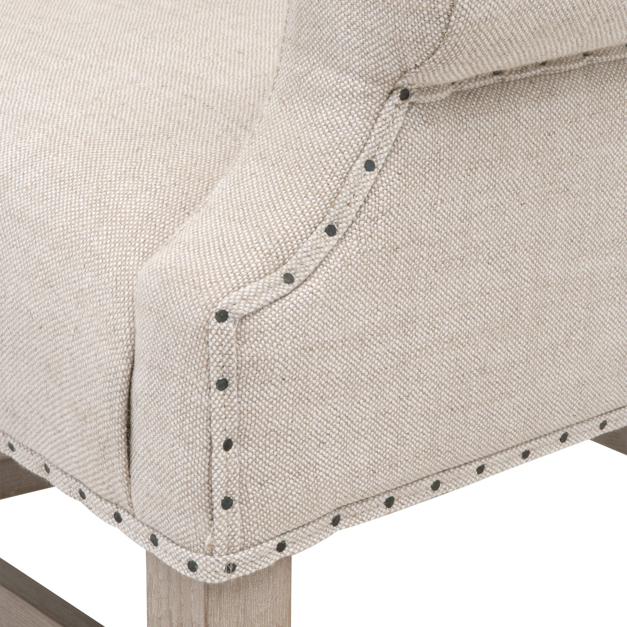 Close-up of Essentials for Living Chateau Arm Chair showing bisque linen upholstery with nail tack accents and natural gray wood frame