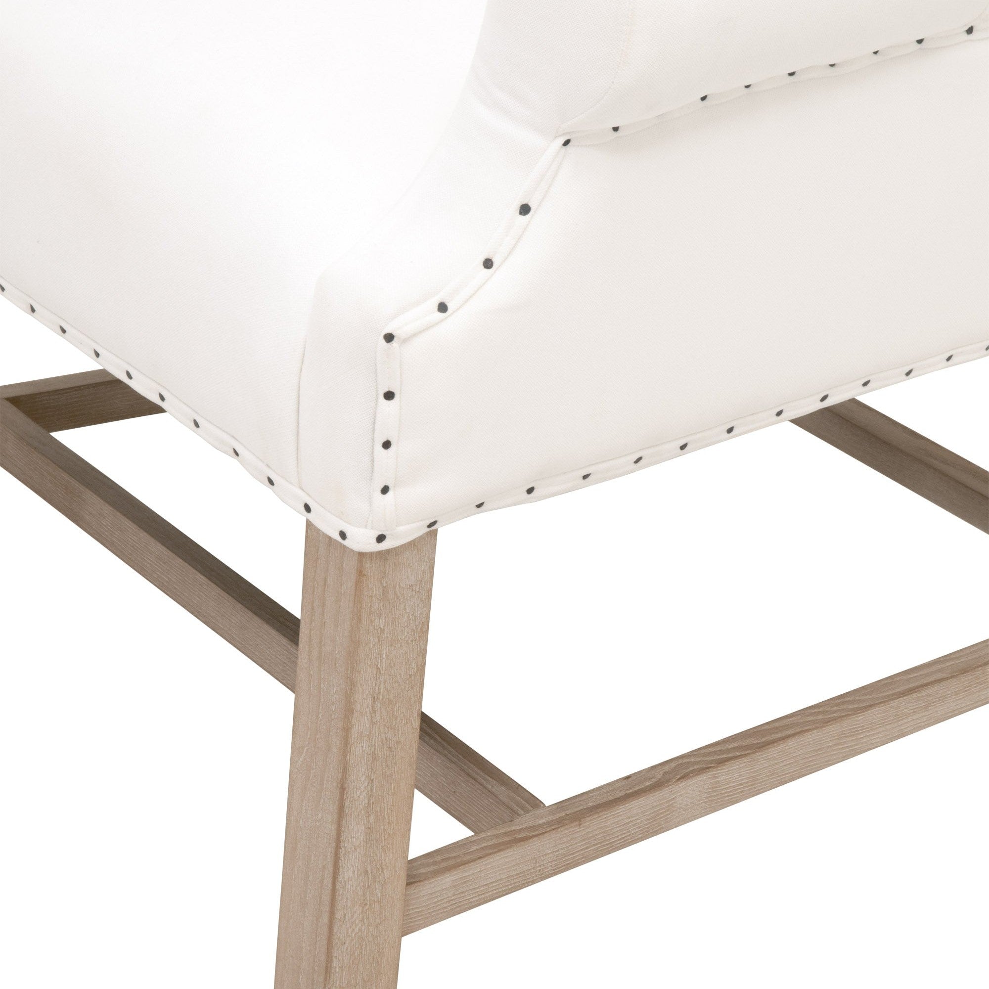 Close-up of Essentials For Living Chateau Arm Chair leg stretchers and bisque linen upholstery with nail tack detailing