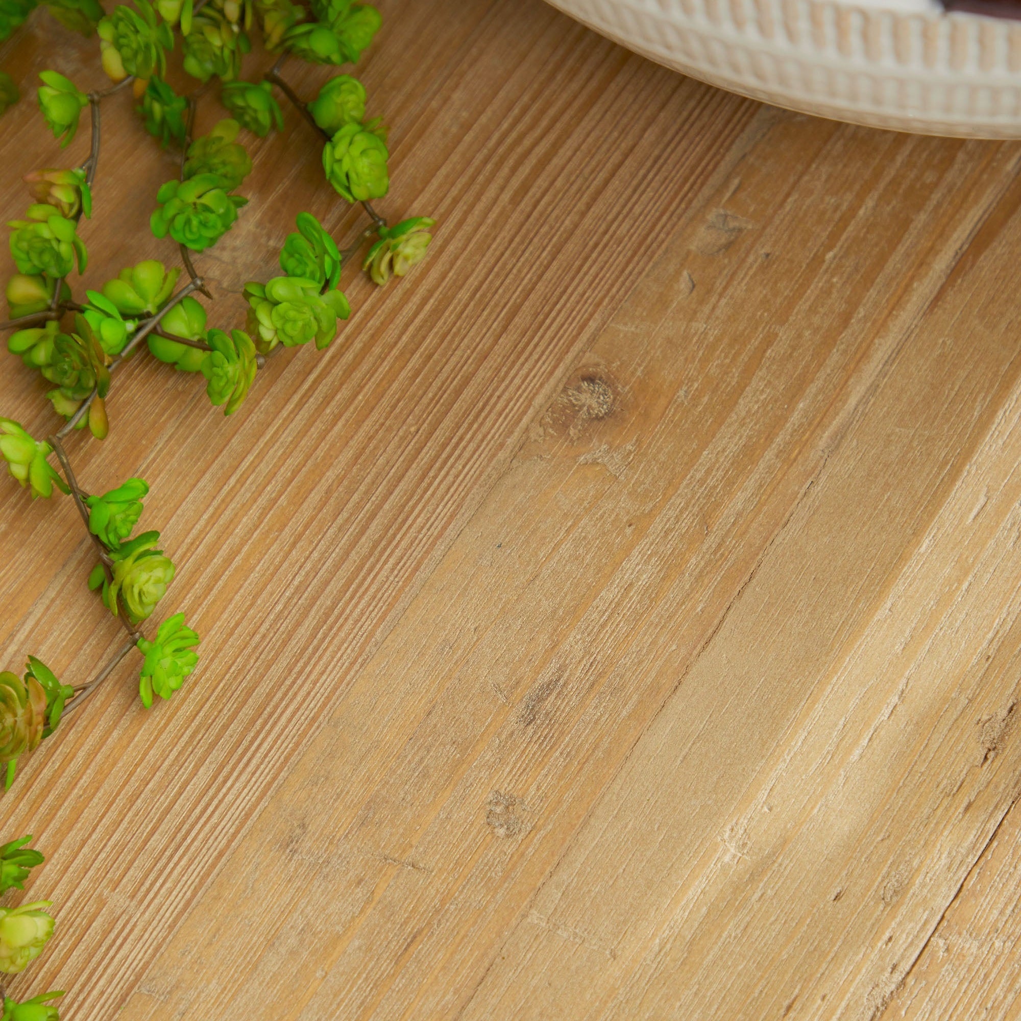 Close-up of reclaimed white pine wood tabletop with natural grain and green plant beside it