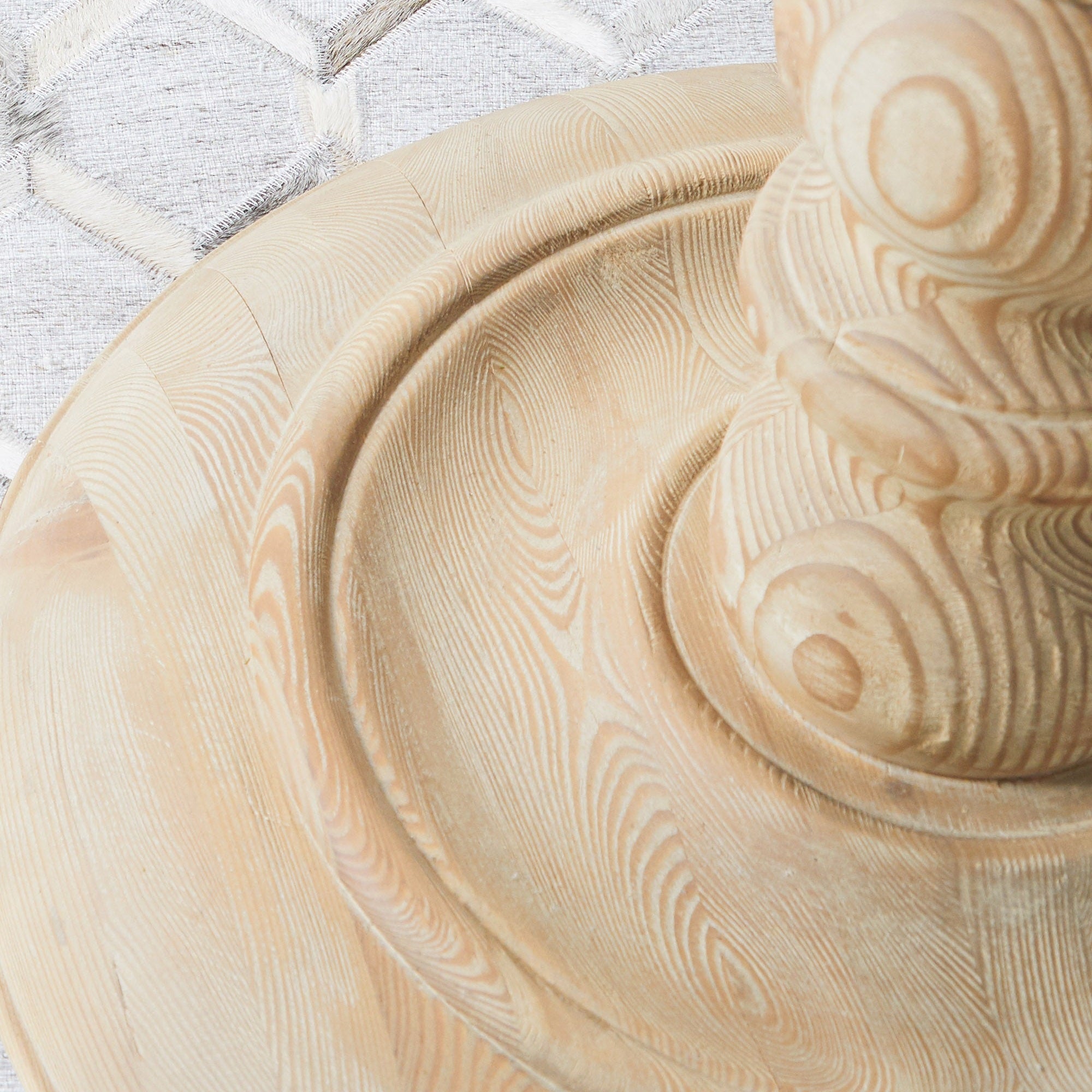 Close-up of the sculpted pedestal base and natural wood grain on the Chelsea 36" round dining table by Essentials For Living