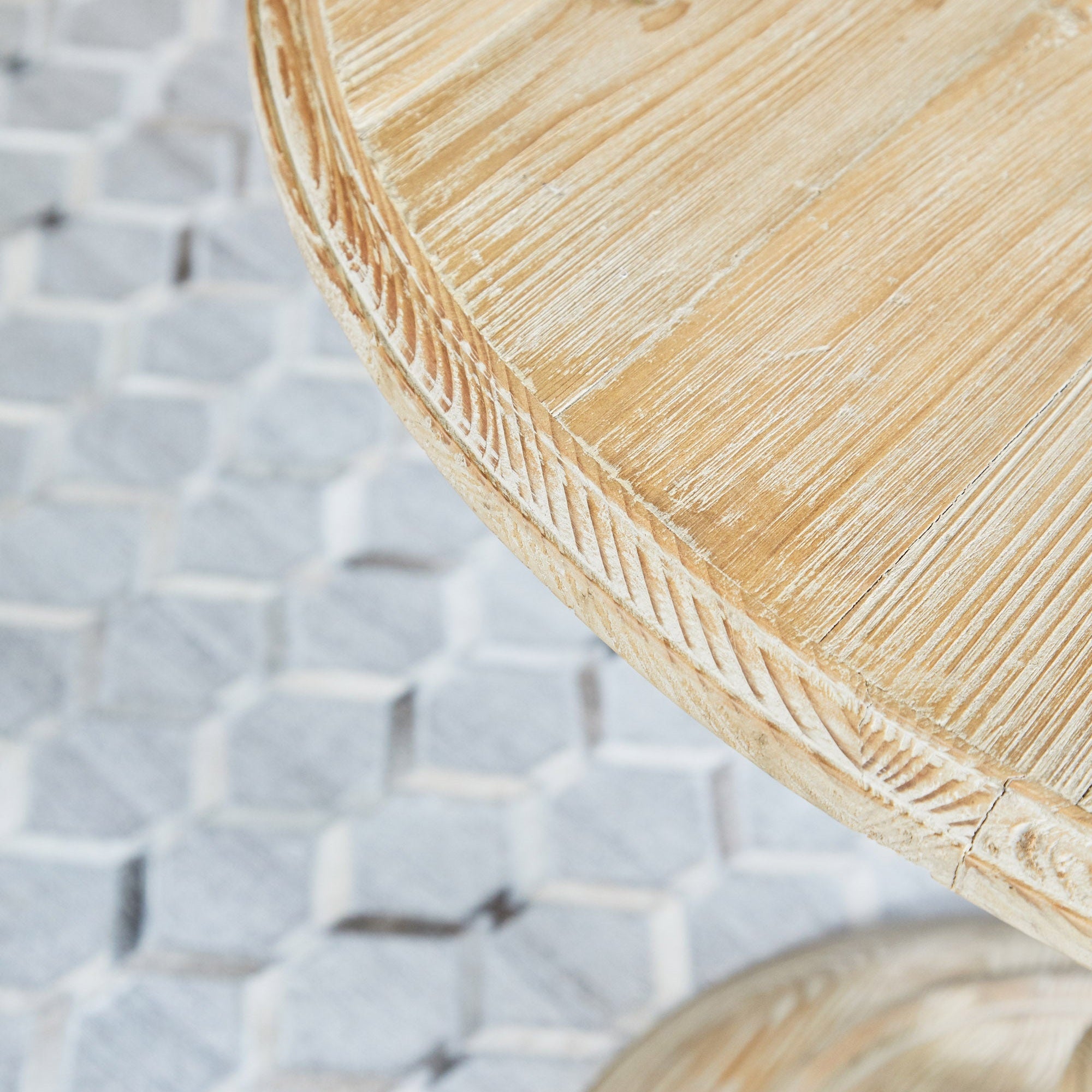 Close-up of reclaimed white pine round dining table edge showcasing rustic carved details and natural finish
