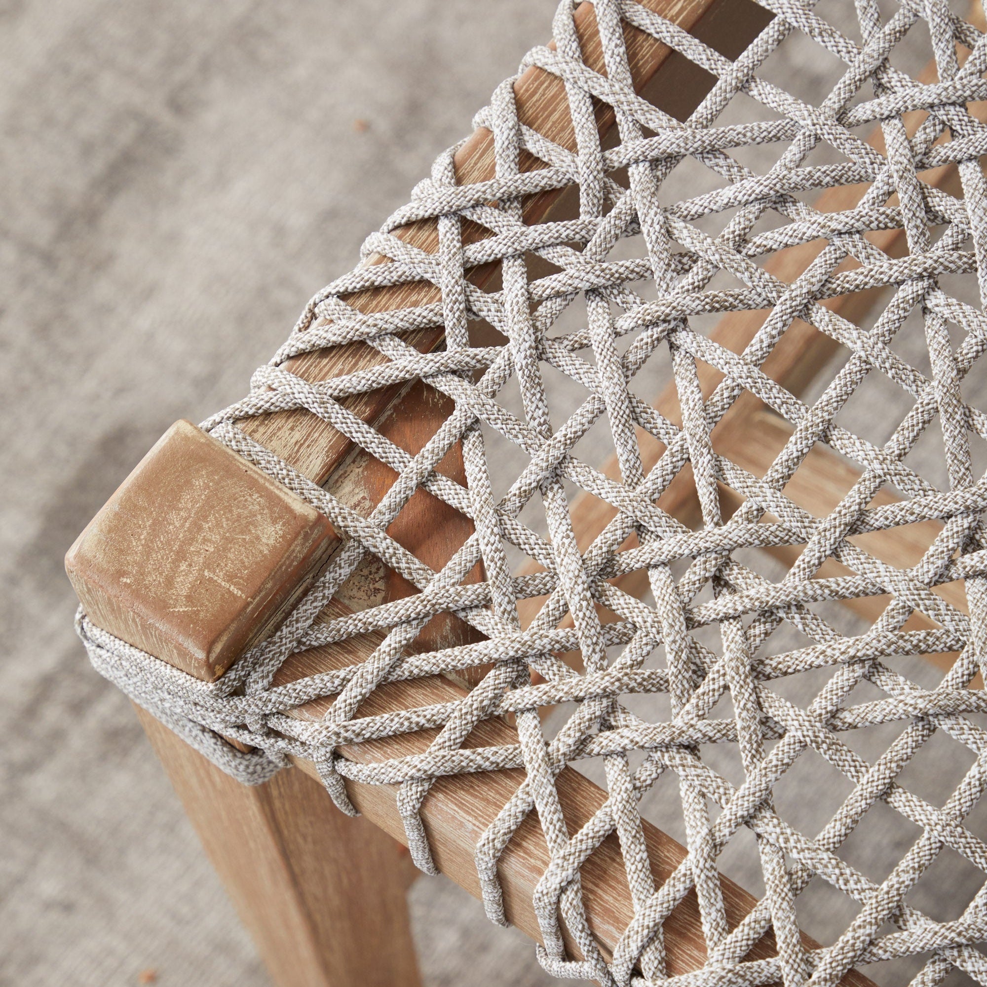 Close-up of the Costa Bench woven white and taupe polypropylene rope seat with natural gray mahogany frame detail