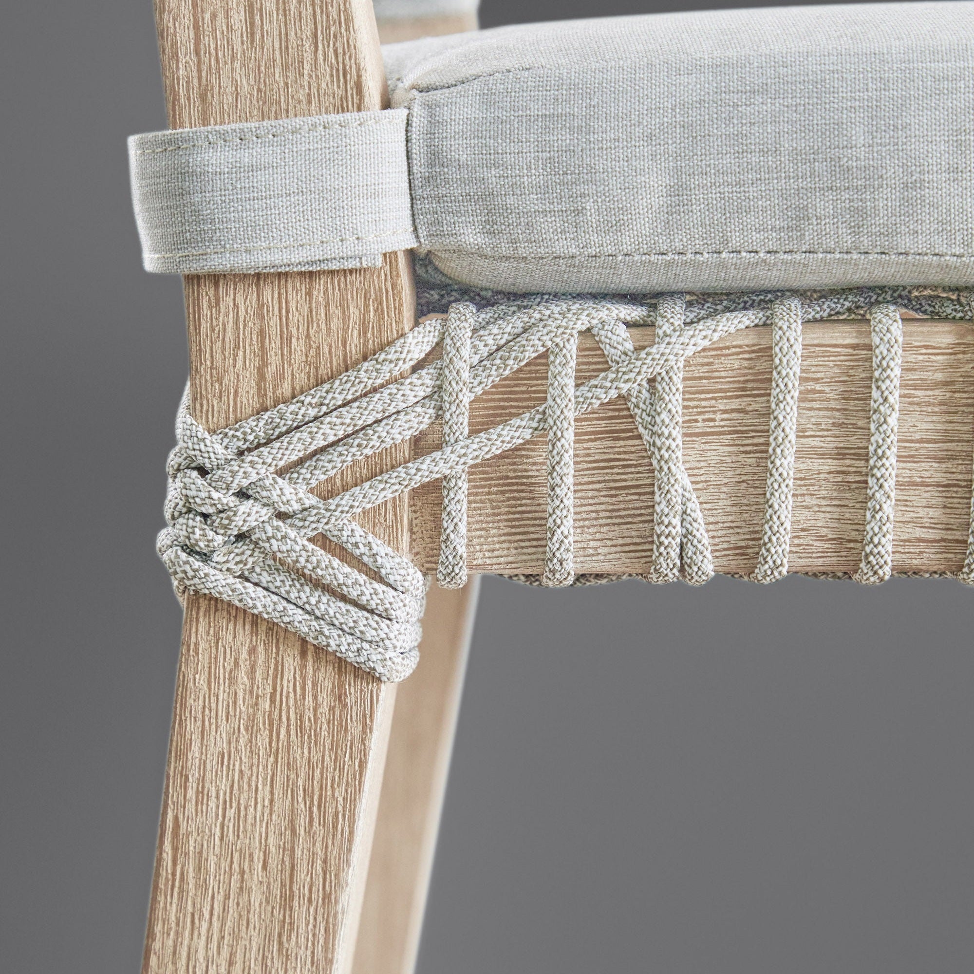 Close-up of Costa Counter Stool corner showing woven taupe polypropylene rope and beige seat cushion strap on wood frame