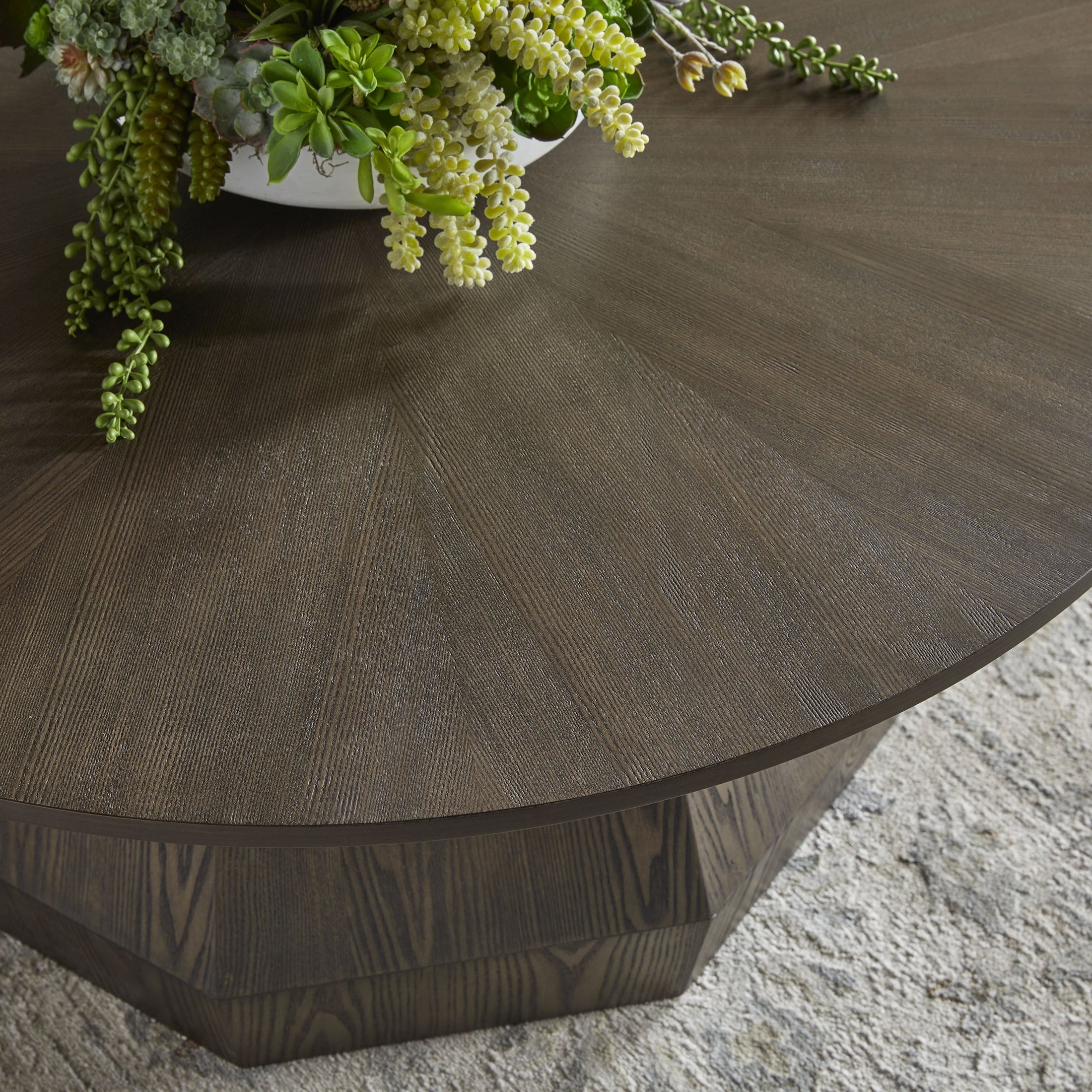 Close-up of the Essentials For Living Coulter Coffee Table's starburst ash veneer tabletop and octagon pedestal base in burnished brown