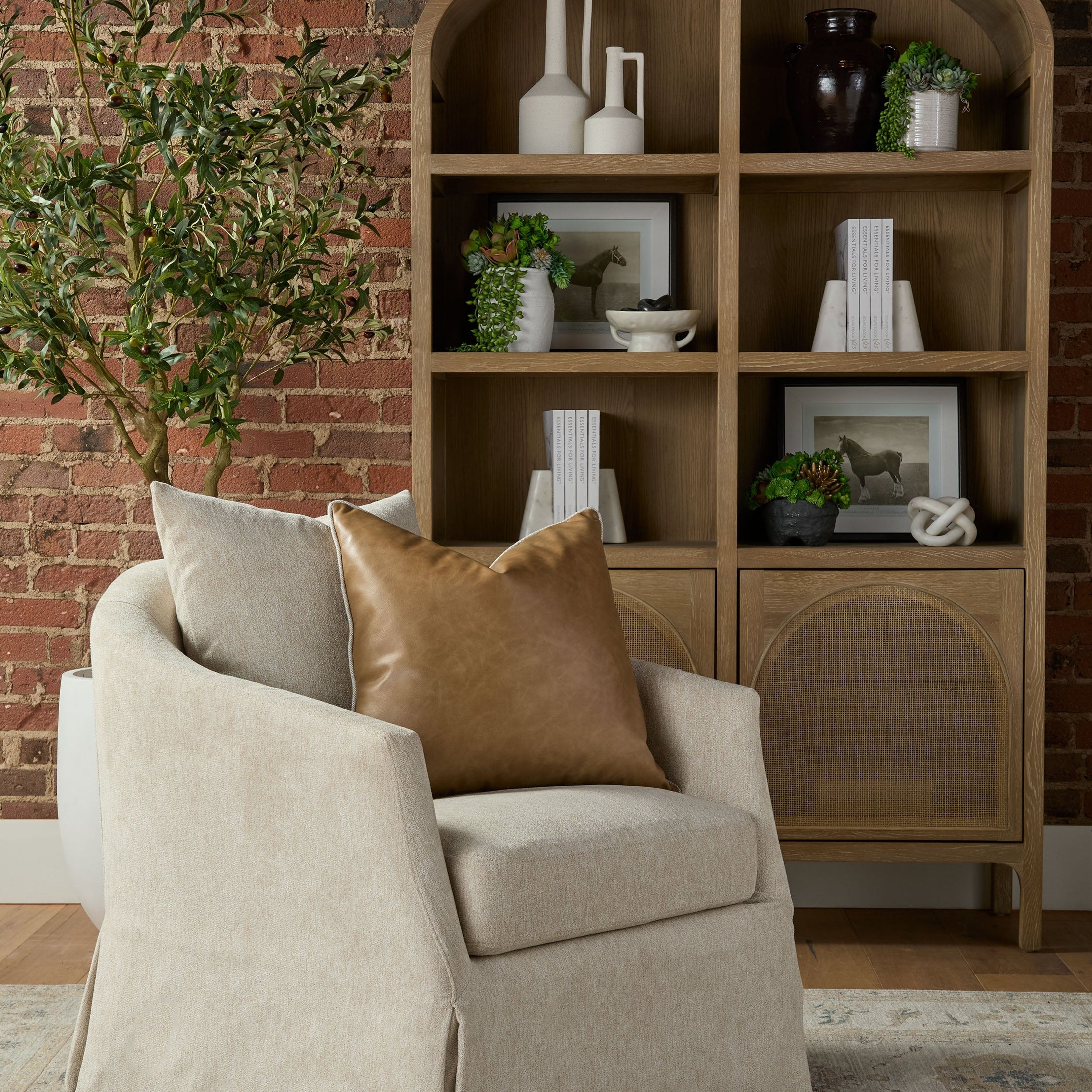 Essentials for Living Faye Slipcover Swivel Club Chair in crème fabric with leather pillow in cozy living room setting