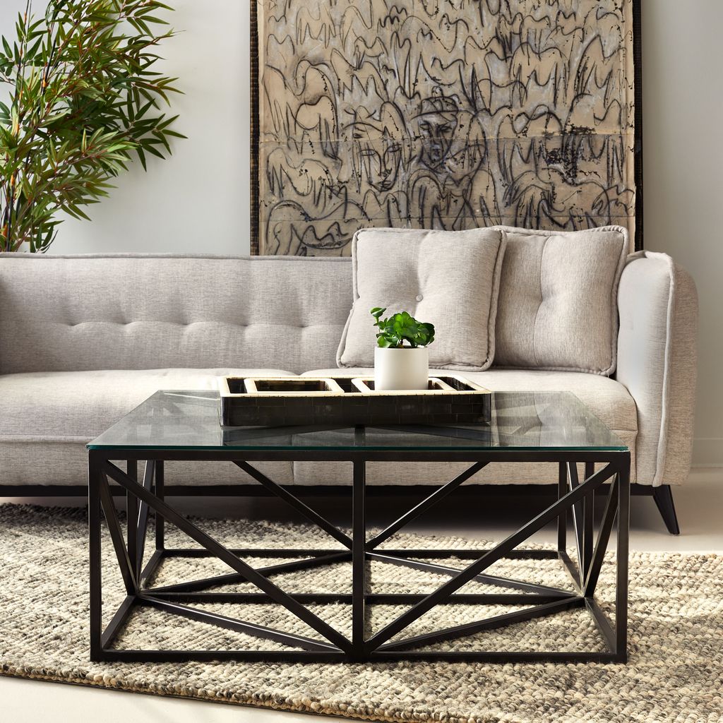 Hanover Glass Coffee Table with black iron crisscross base and clear tempered glass top in a modern living room by GO HOME