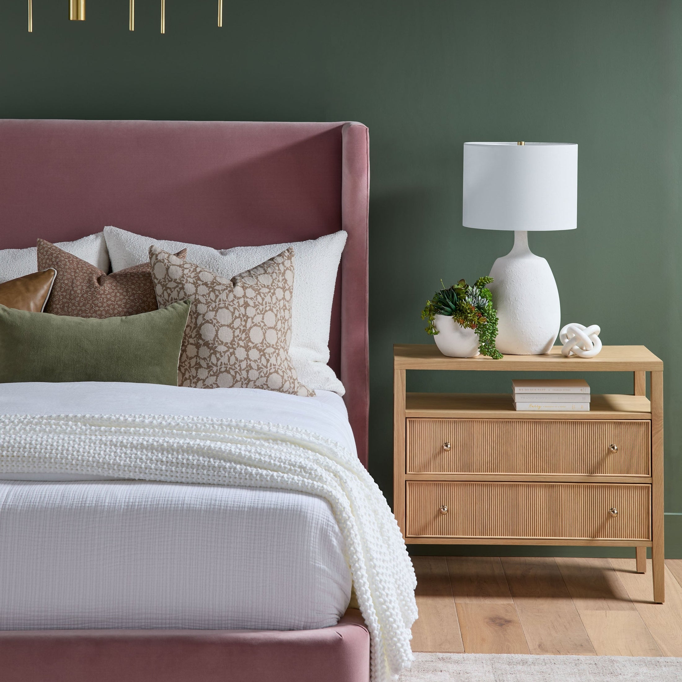 Essentials For Living Highland nightstand in light oak with two drawers, open shelf, and modern decor on top next to a bed