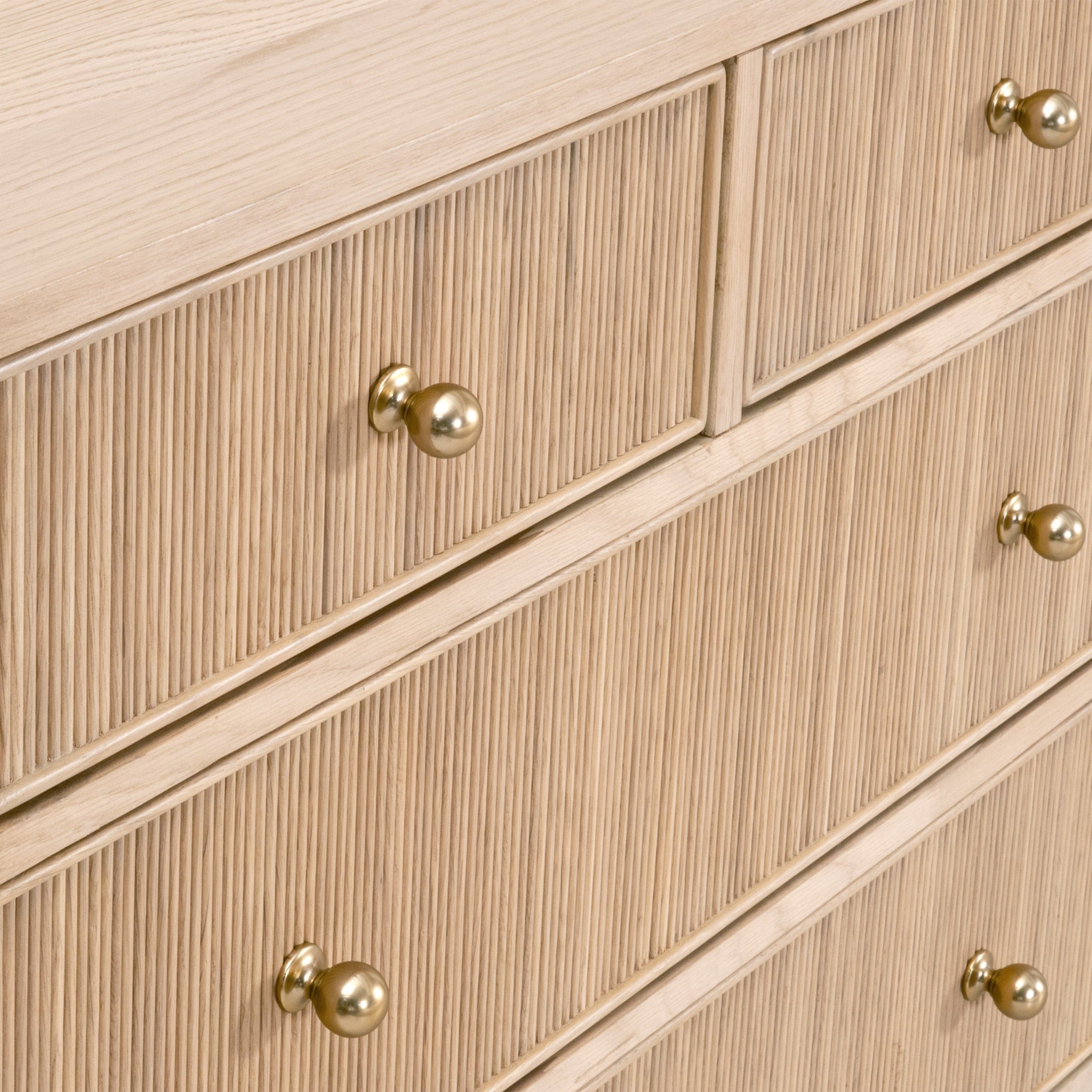 Close-up of a natural oak Highland double dresser featuring fluted drawer fronts and polished brass iron knobs.