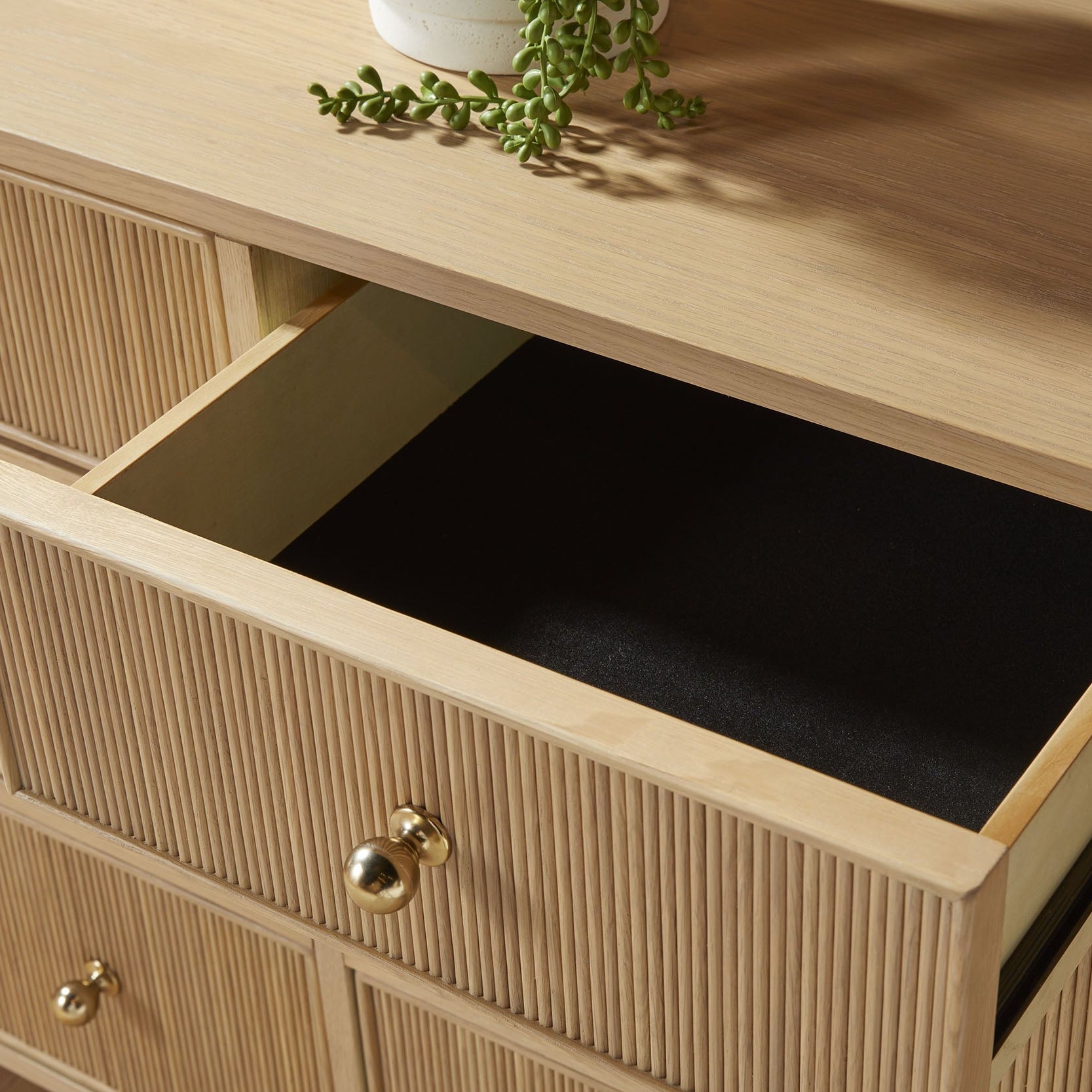Open top drawer of Highland 8-Drawer Double Dresser showing felt lining and fluted oak wood front with brass knobs