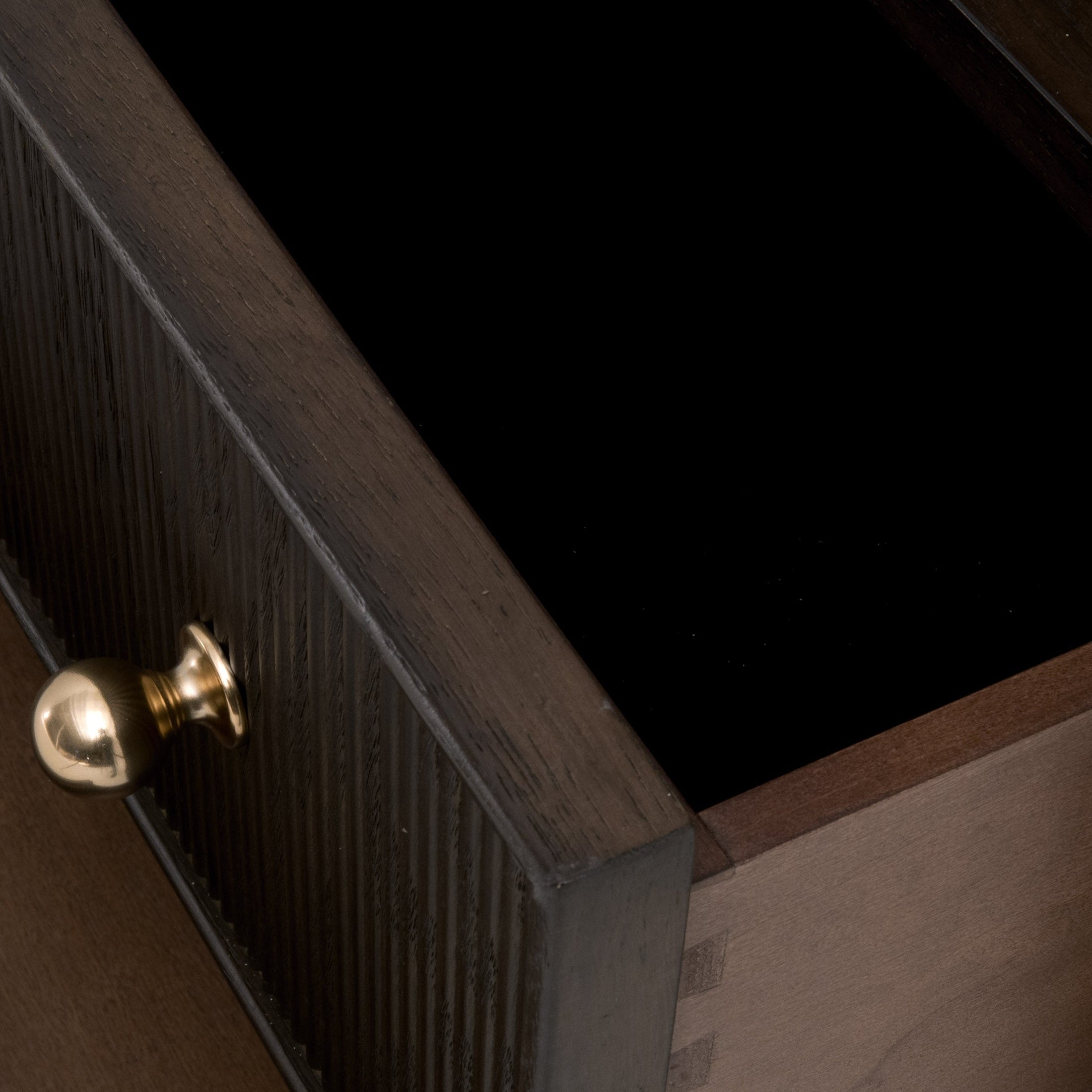 Close-up of open drawer with fluted wood front and polished brass knob on Dutch Brown Oak nightstand by Essentials For Living