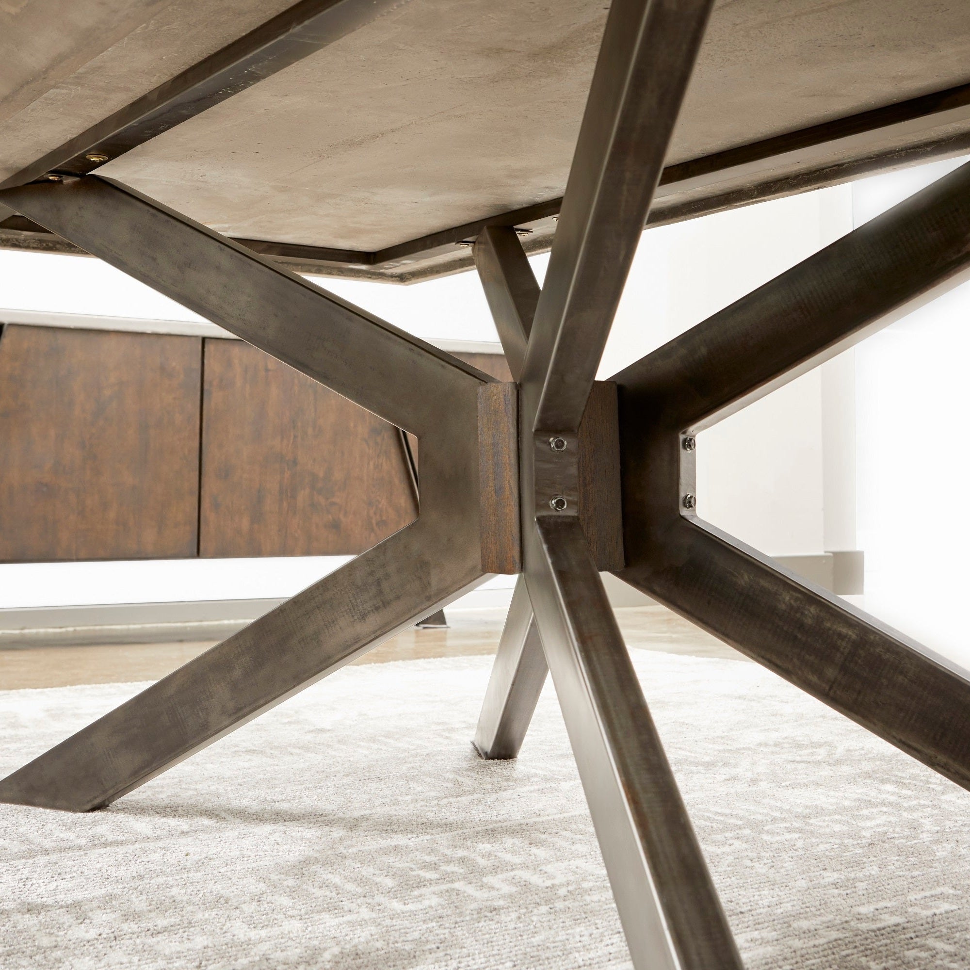 Close-up of distressed black iron base with cross-bracing supporting Industry Rectangle Dining Table by Essentials For Living