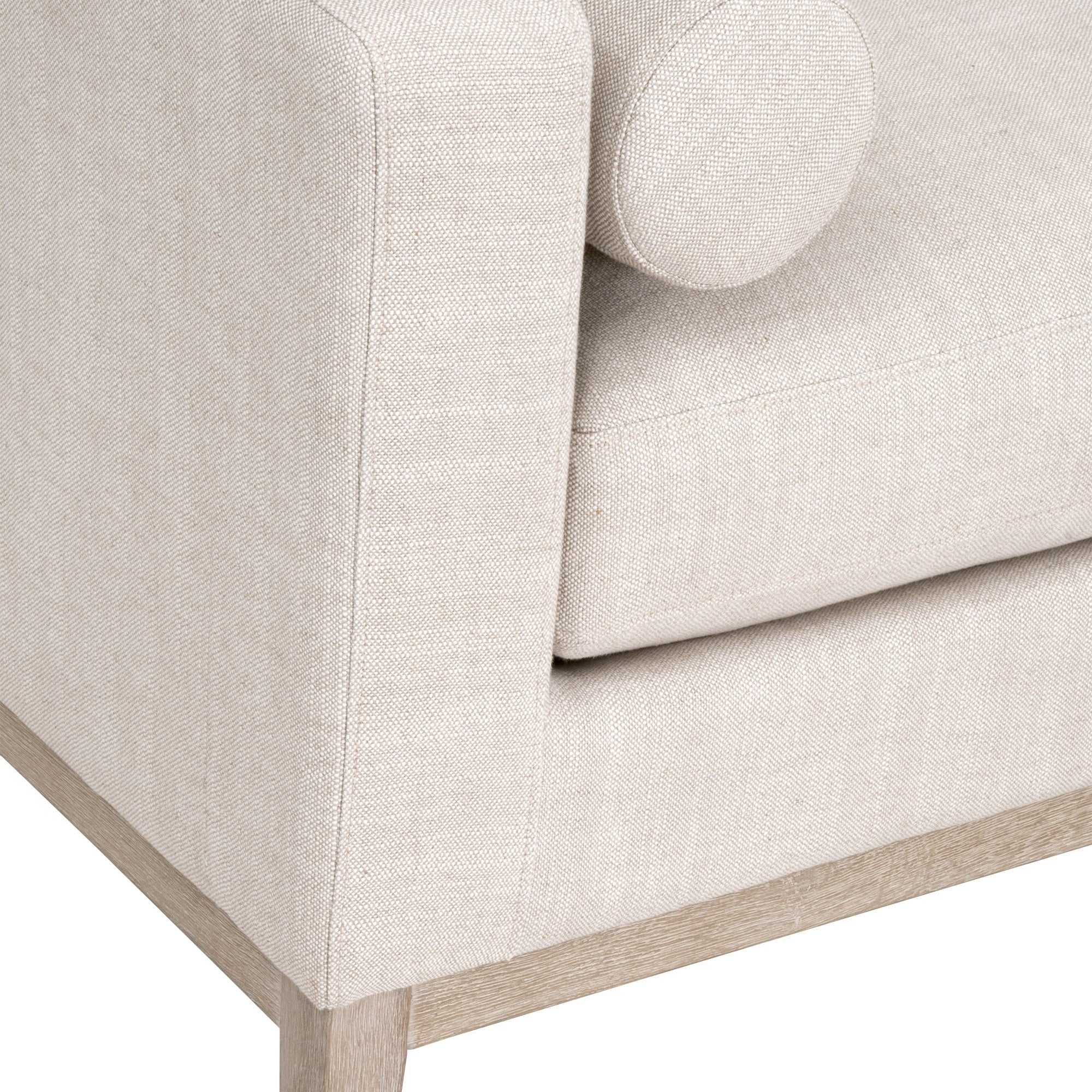 Close-up of bisque fabric upholstery and wooden base on the Essentials For Living Keaton Daybed with round bolster pillow
