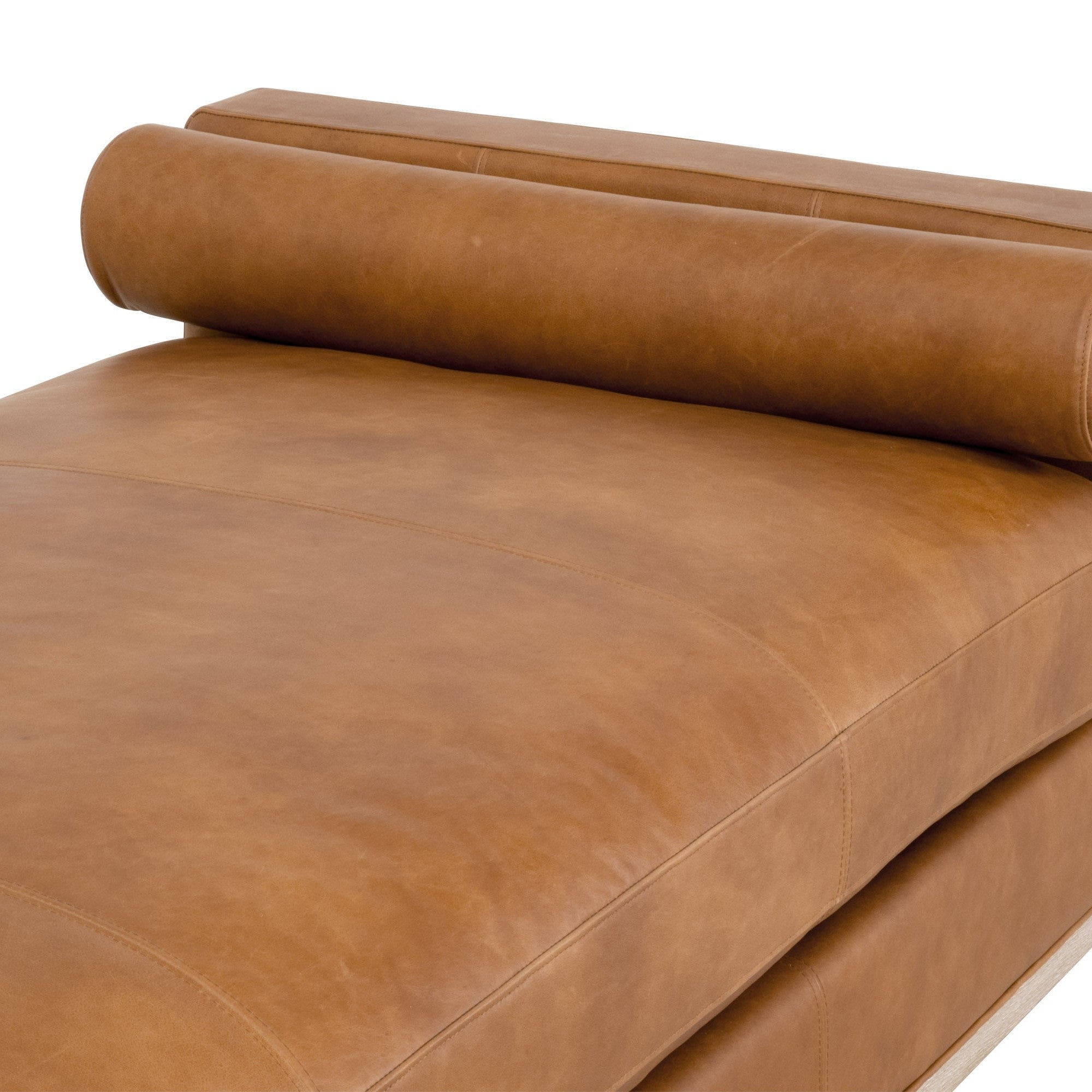 Close-up view of a sleek brown leather daybed with a cylindrical bolster pillow by Essentials For Living