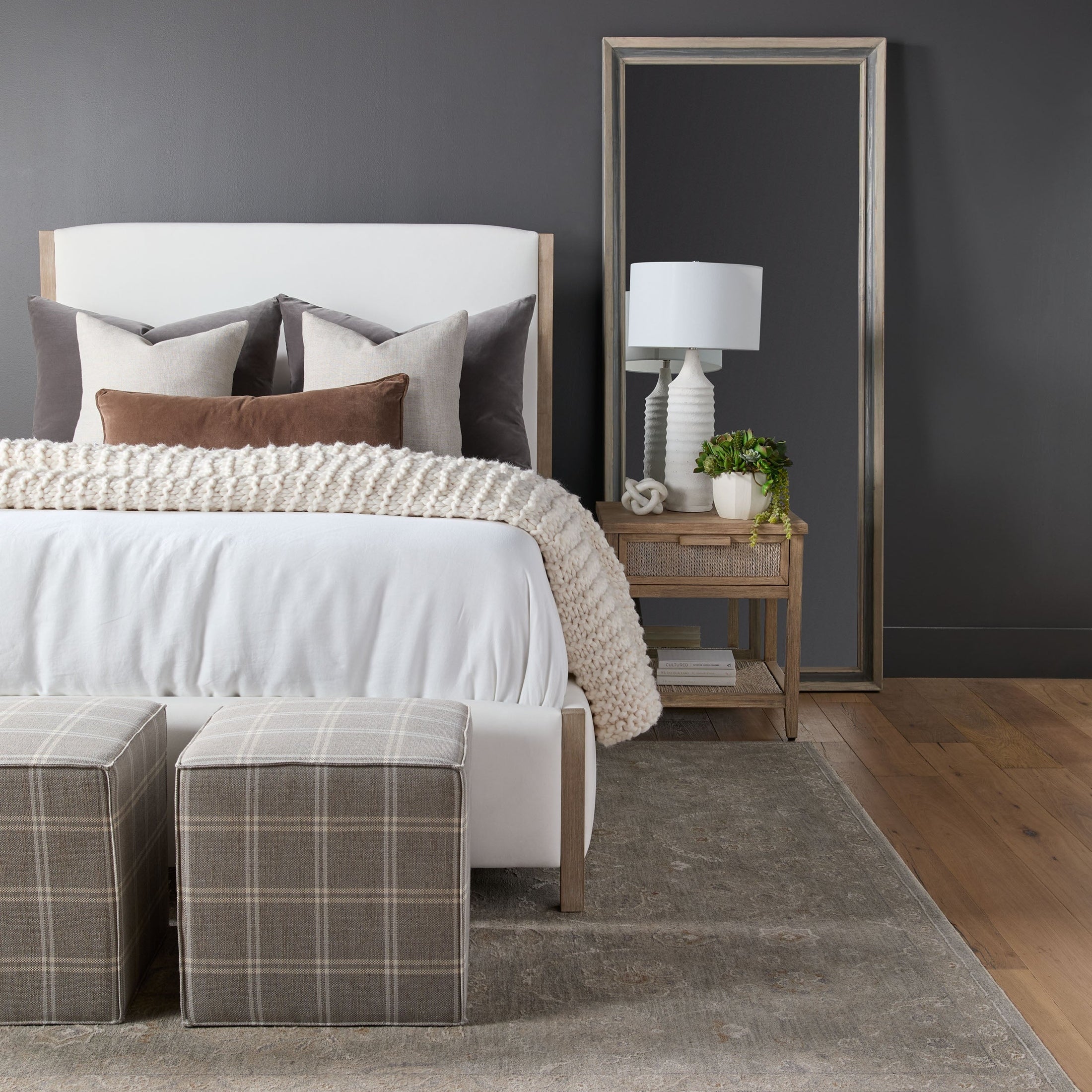 Two Knox Accent Cubes upholstered in neutral plaid fabric placed in a stylish bedroom setting by Essentials for Living.