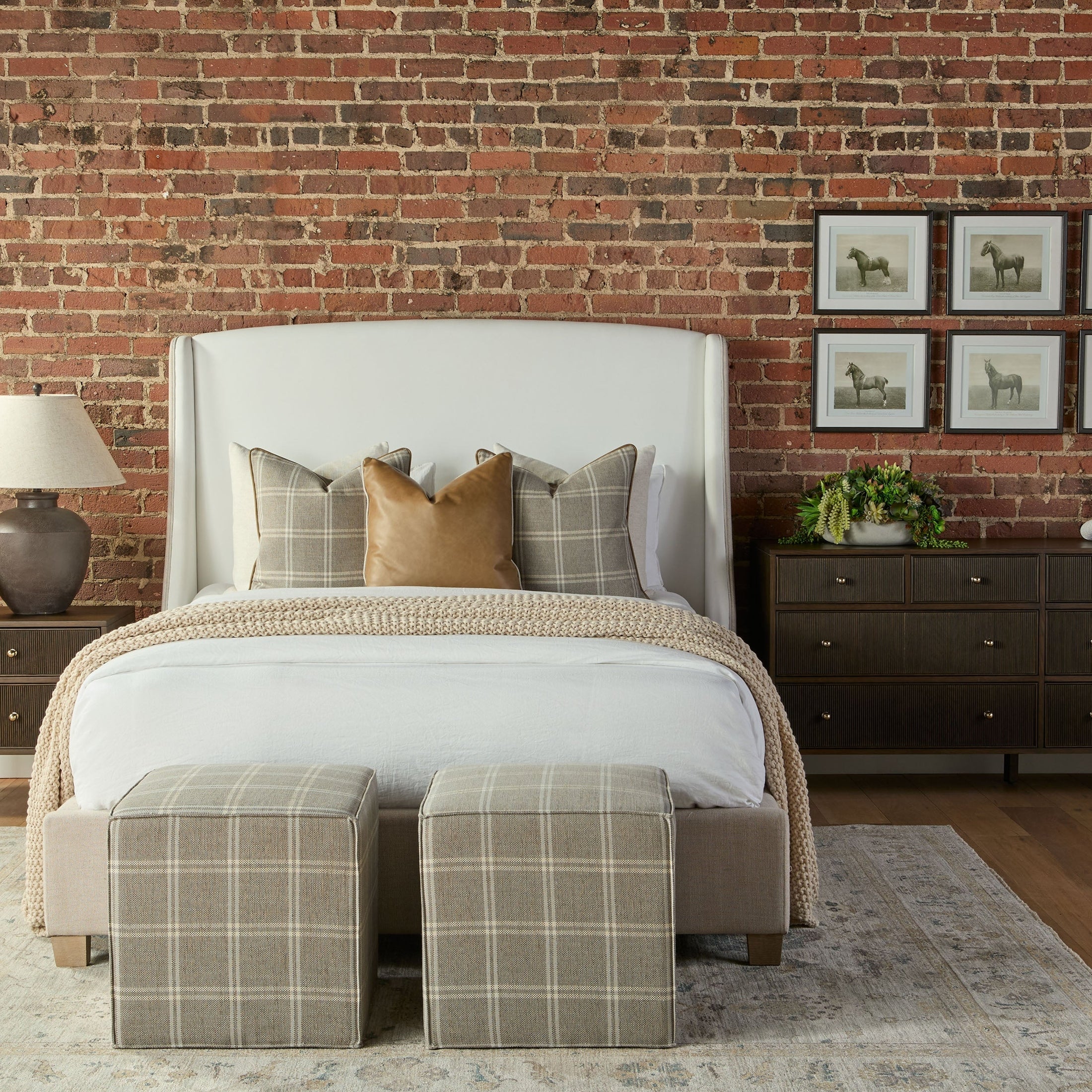 Two plaid Knox Accent Cubes at the foot of a beige upholstered bed in a stylish bedroom setting