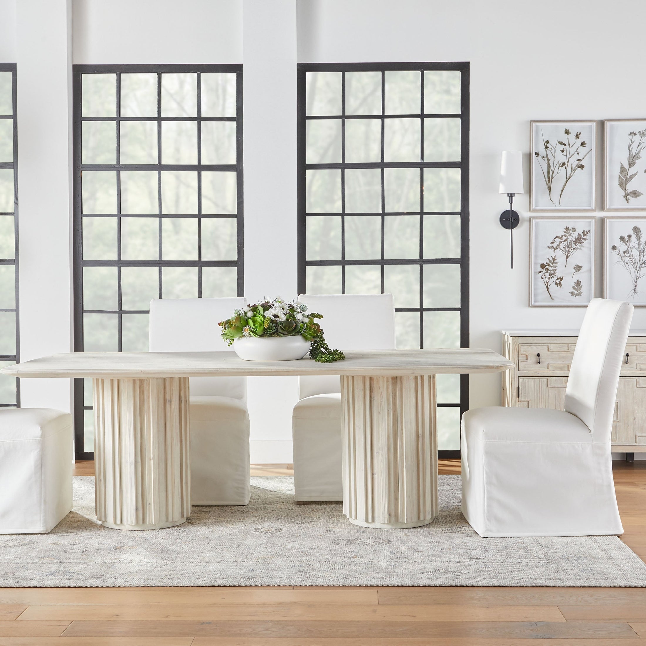 Two white Levi slipcover dining chairs set around a modern table in a bright dining room by Essentials for Living
