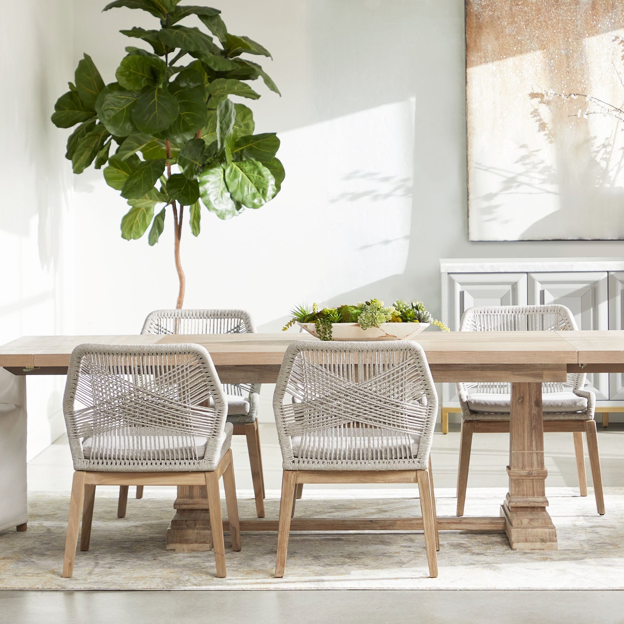 Set of two Loom Dining Chairs with woven taupe and white seats and natural gray wood legs around wooden table