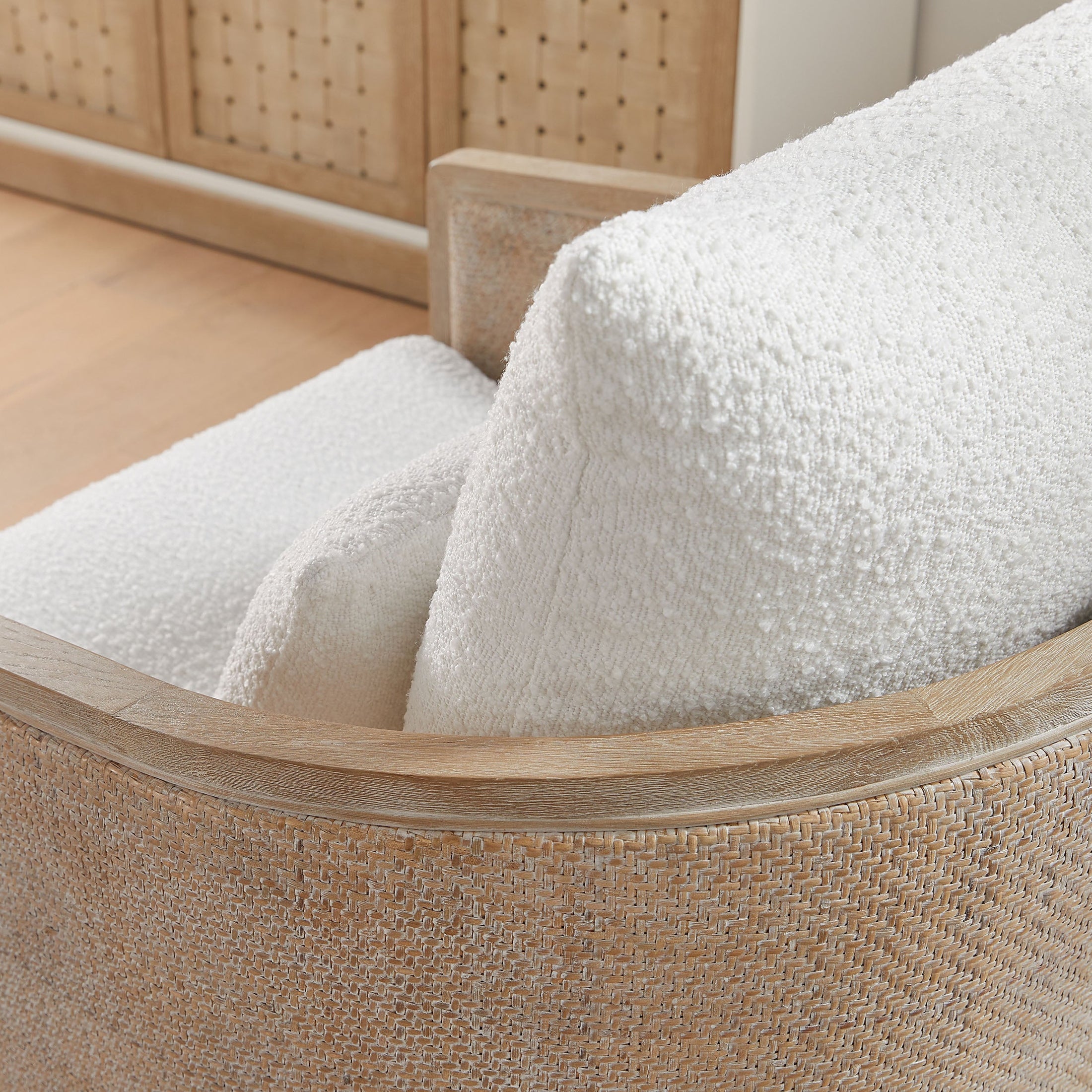 Close-up of McGuire Swivel Club Chair showing natural gray cane frame and soft white boucle upholstery cushion by Essentials for Living