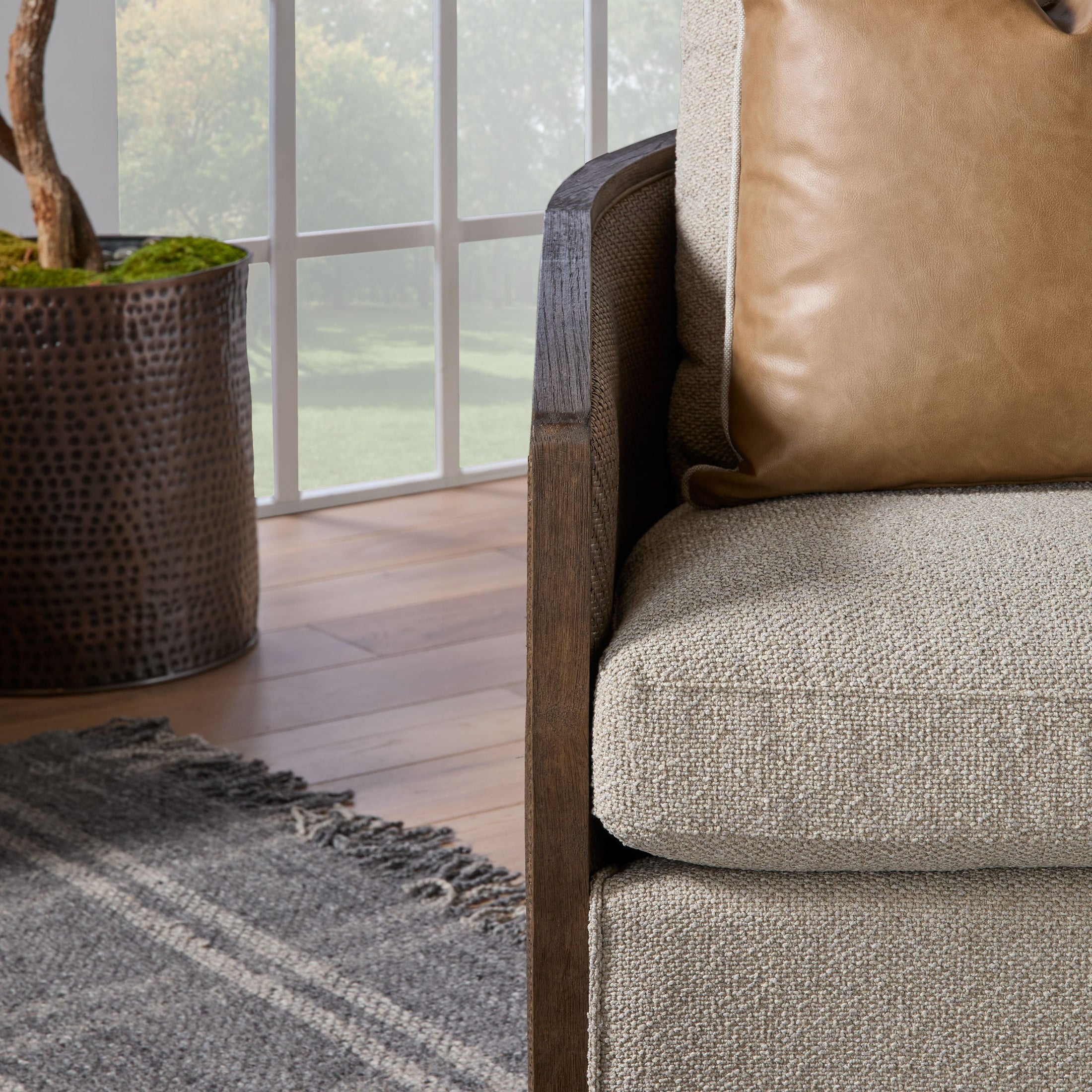 Close-up of McGuire Swivel Club Chair showing textured boucle cushion and solid oak armrest in cozy living space