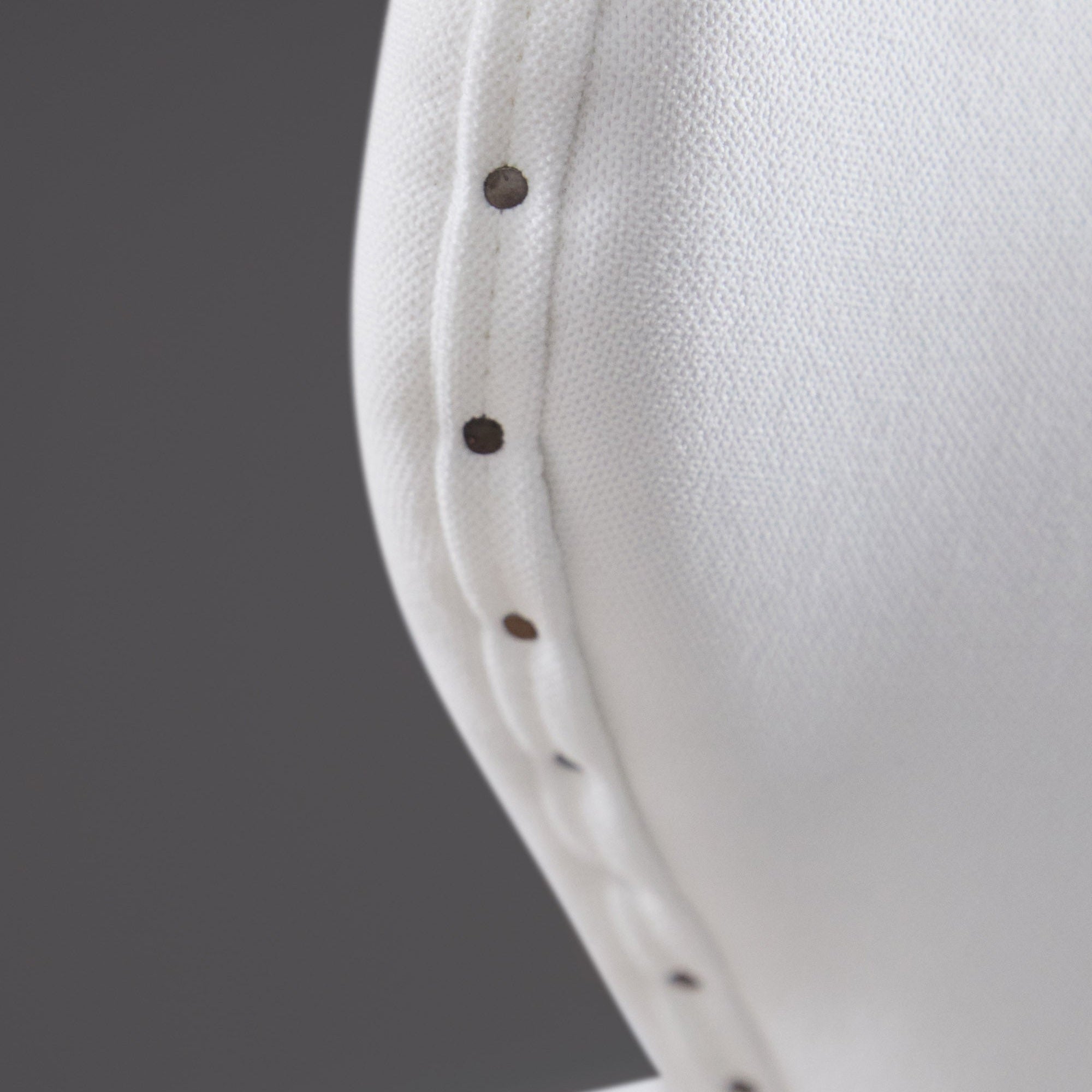 Close-up of Bisque French Linen upholstery with black nail-tack trim on Milton Swivel Counter Stool by Essentials For Living