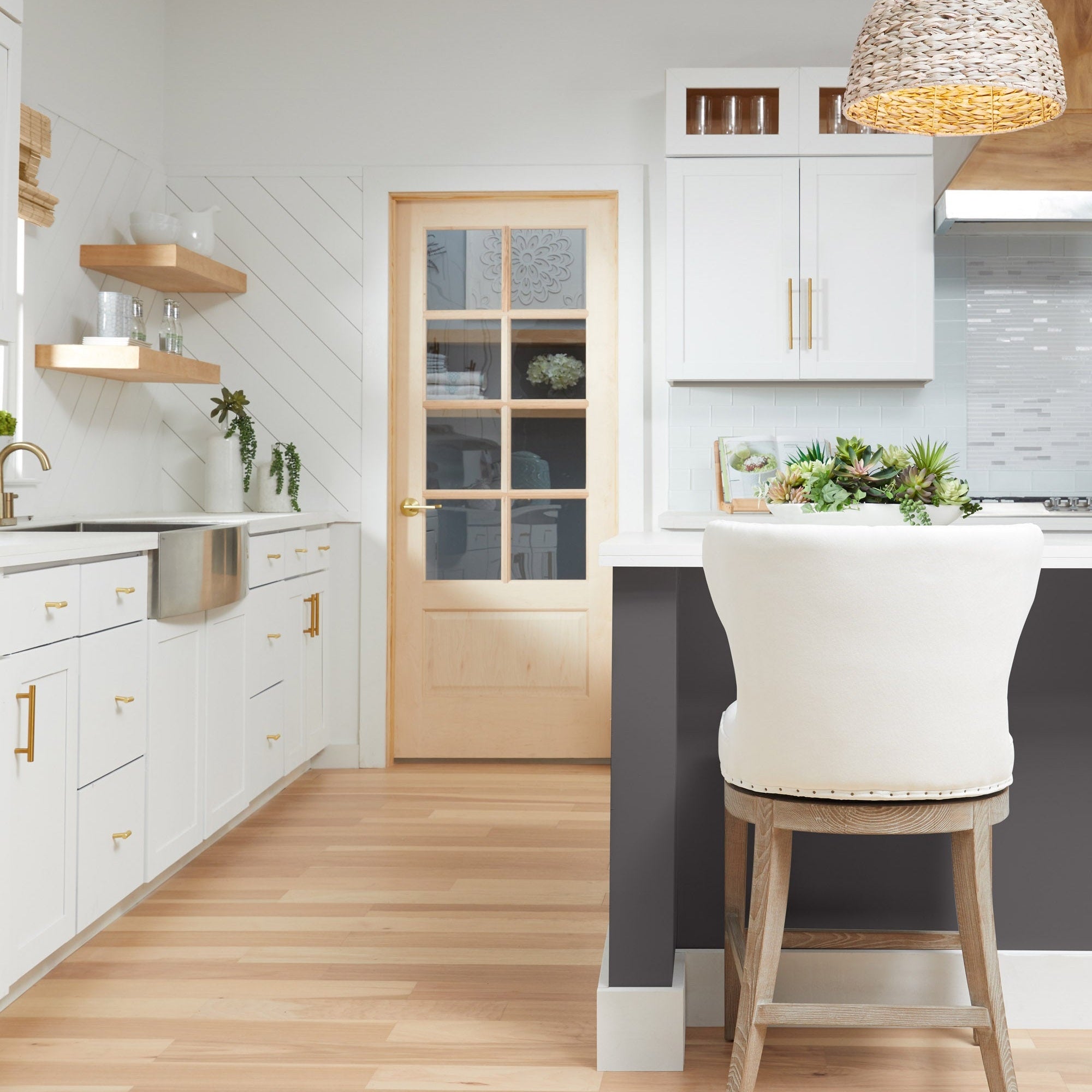 Milton swivel counter stool with Bisque French Linen upholstery and black nail-tack trim in modern kitchen setting