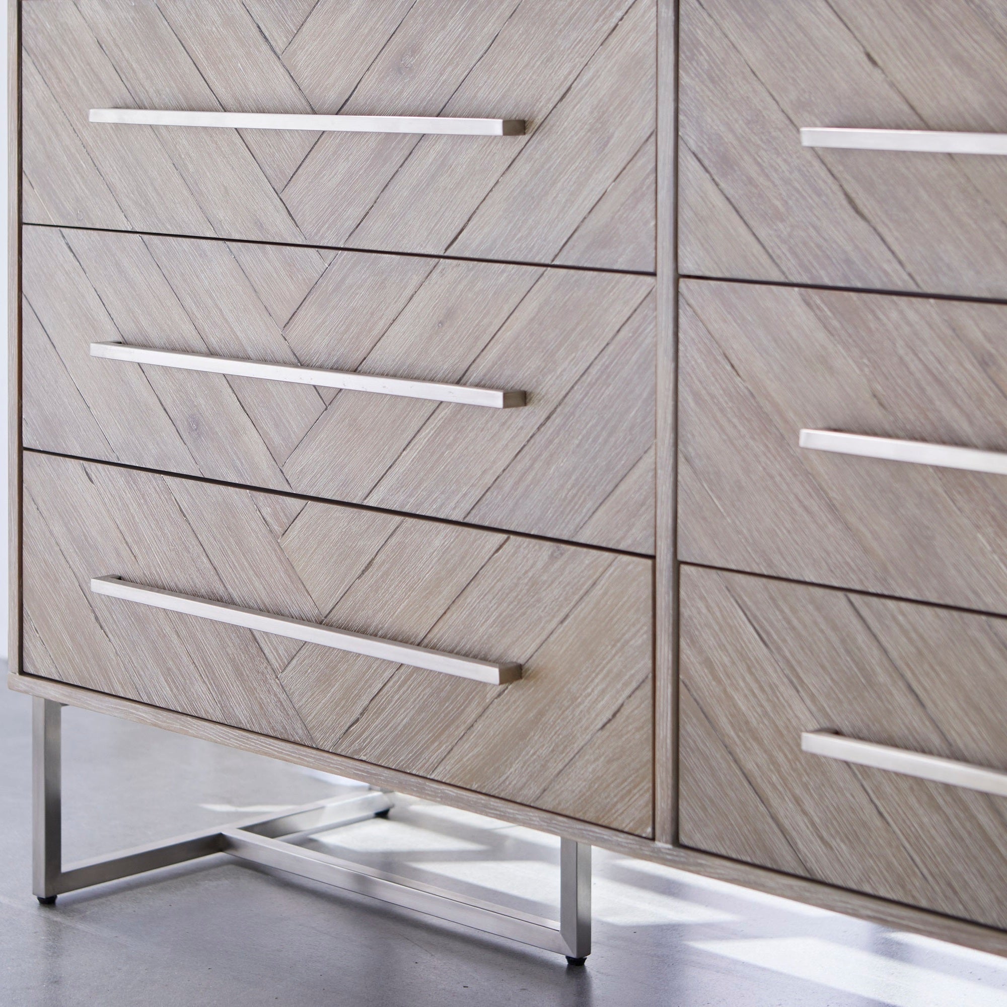 Close-up of Mosaic 6-Drawer Double Dresser with herringbone gray acacia veneer and stainless steel base by Essentials for Living