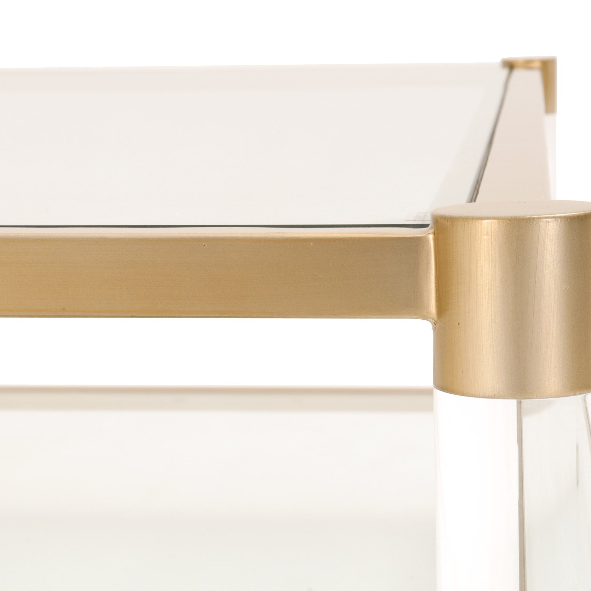 Close-up of Nouveau Coffee Table with brushed brass frame, clear tempered glass top, and Lucite legs by Essentials for Living