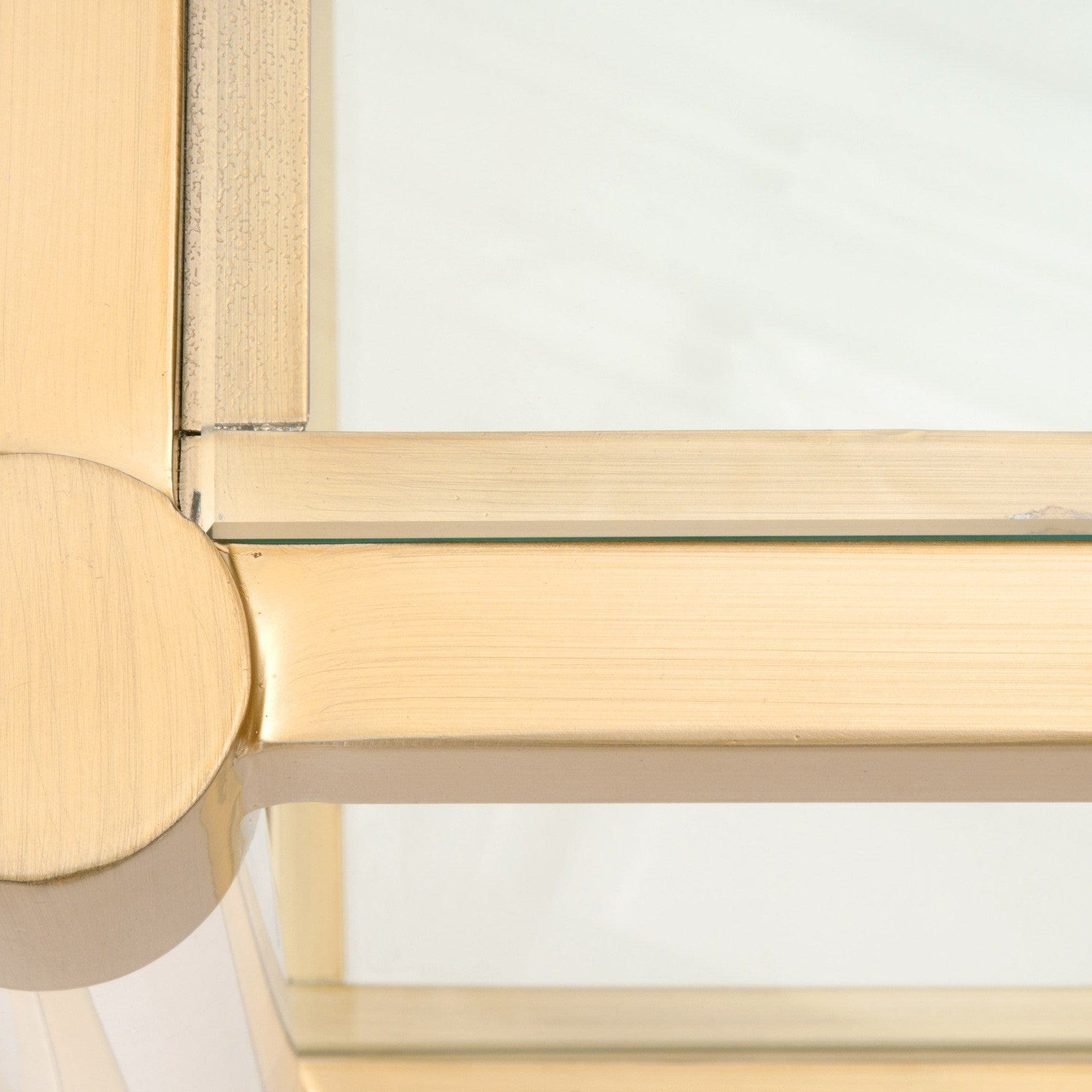 Close-up of Nouveau Coffee Table brushed brass frame, clear tempered glass, and Lucite legs by Essentials for Living.
