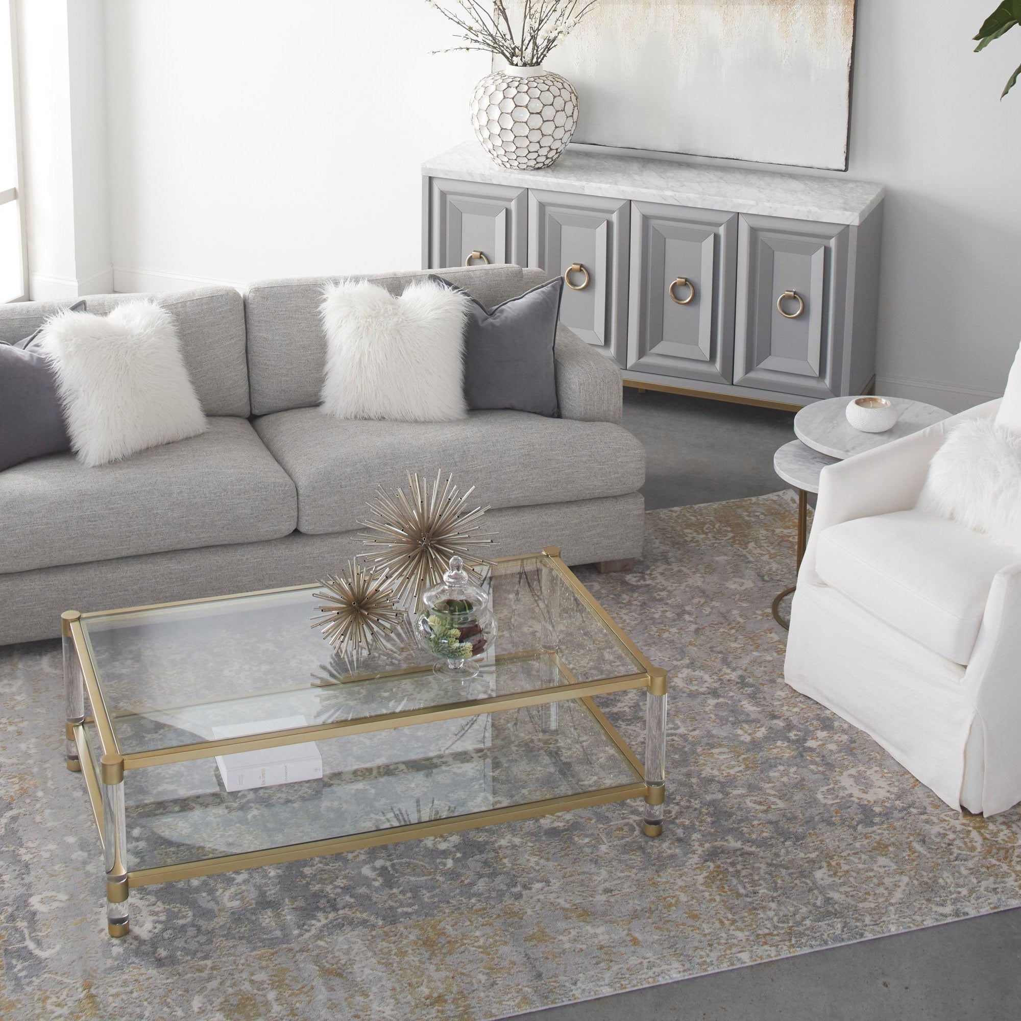 Nouveau Coffee Table with brushed brass frame, clear tempered glass top, Lucite legs in modern living room by Essentials for Living