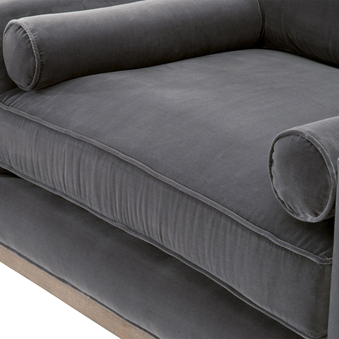 Close-up of plush gray velvet sofa chair cushion with cylindrical bolster pillows and natural wood base
