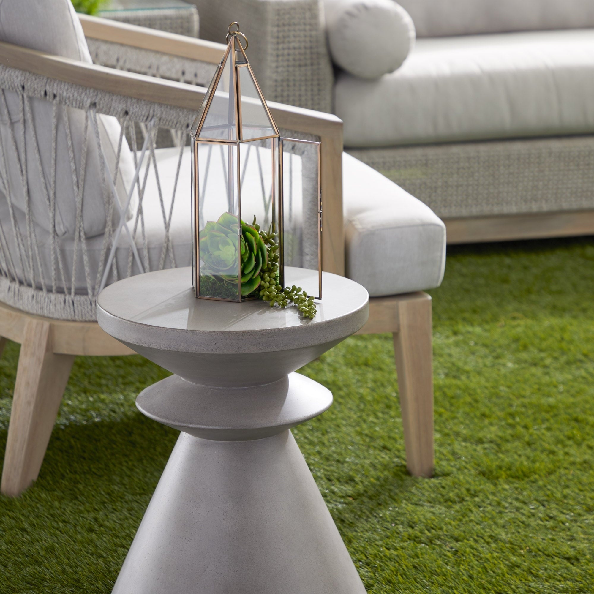 Ivory nano-sealed concrete Pawn Accent Table by Essentials For Living next to outdoor seating on green grass