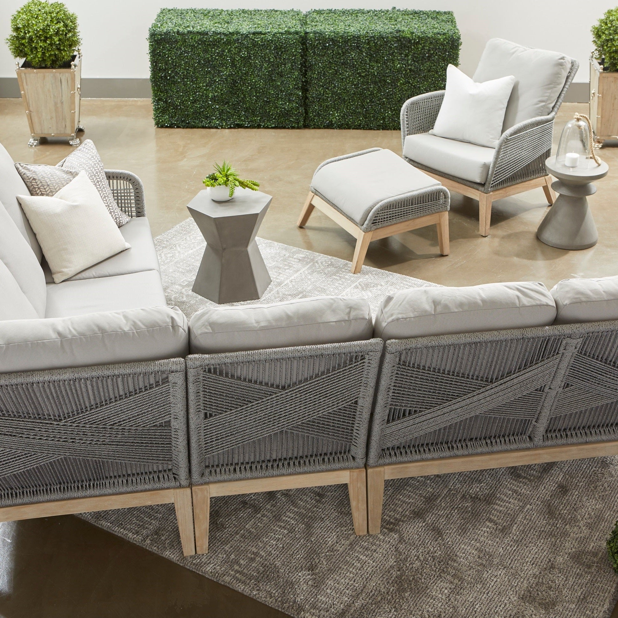 Essentials for Living Pawn Accent Table in ivory nano-sealed concrete beside outdoor woven armchair with cushions.