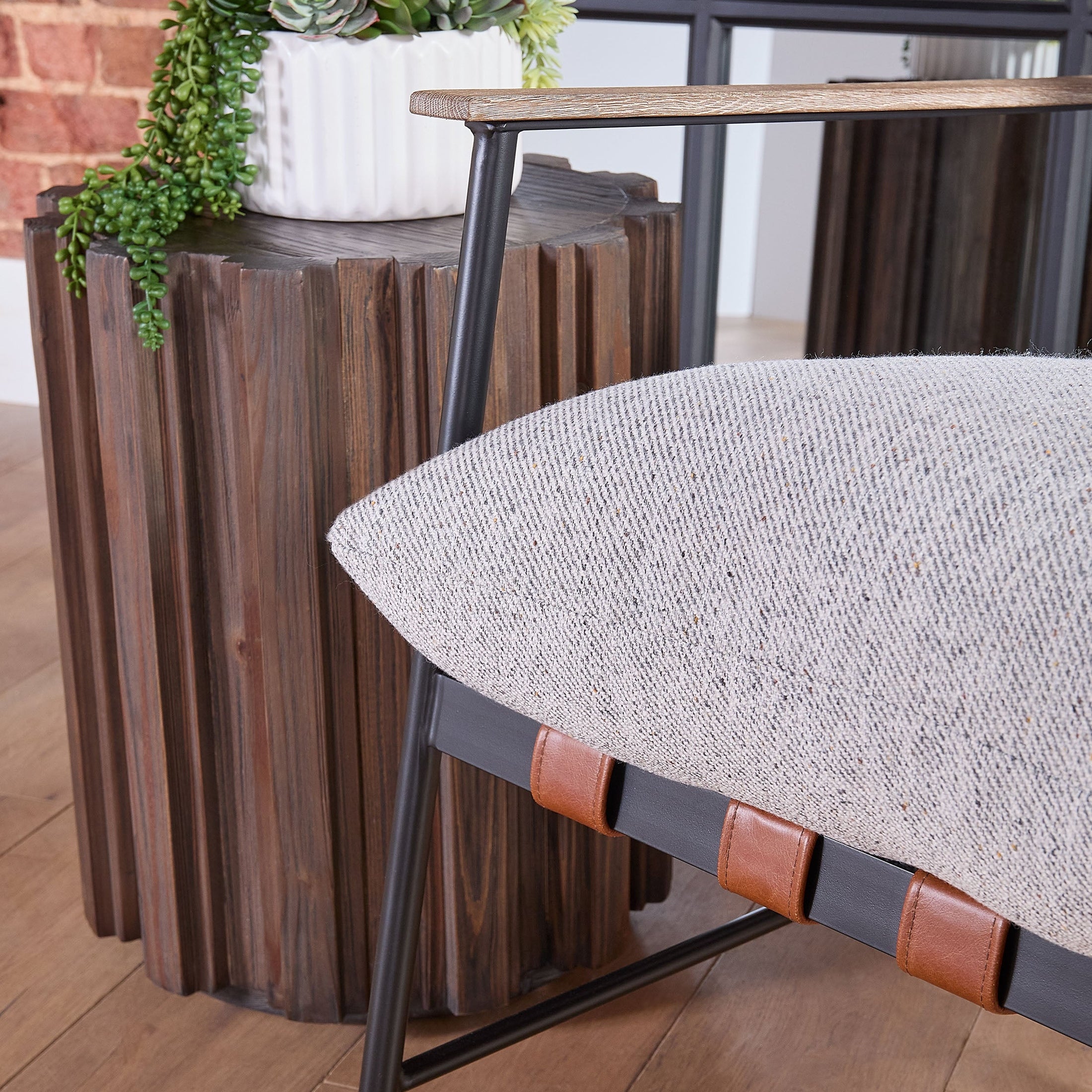 Close-up of Roma Accent Table by Essentials for Living with textured reclaimed wood and decorative fluting next to chair cushion.