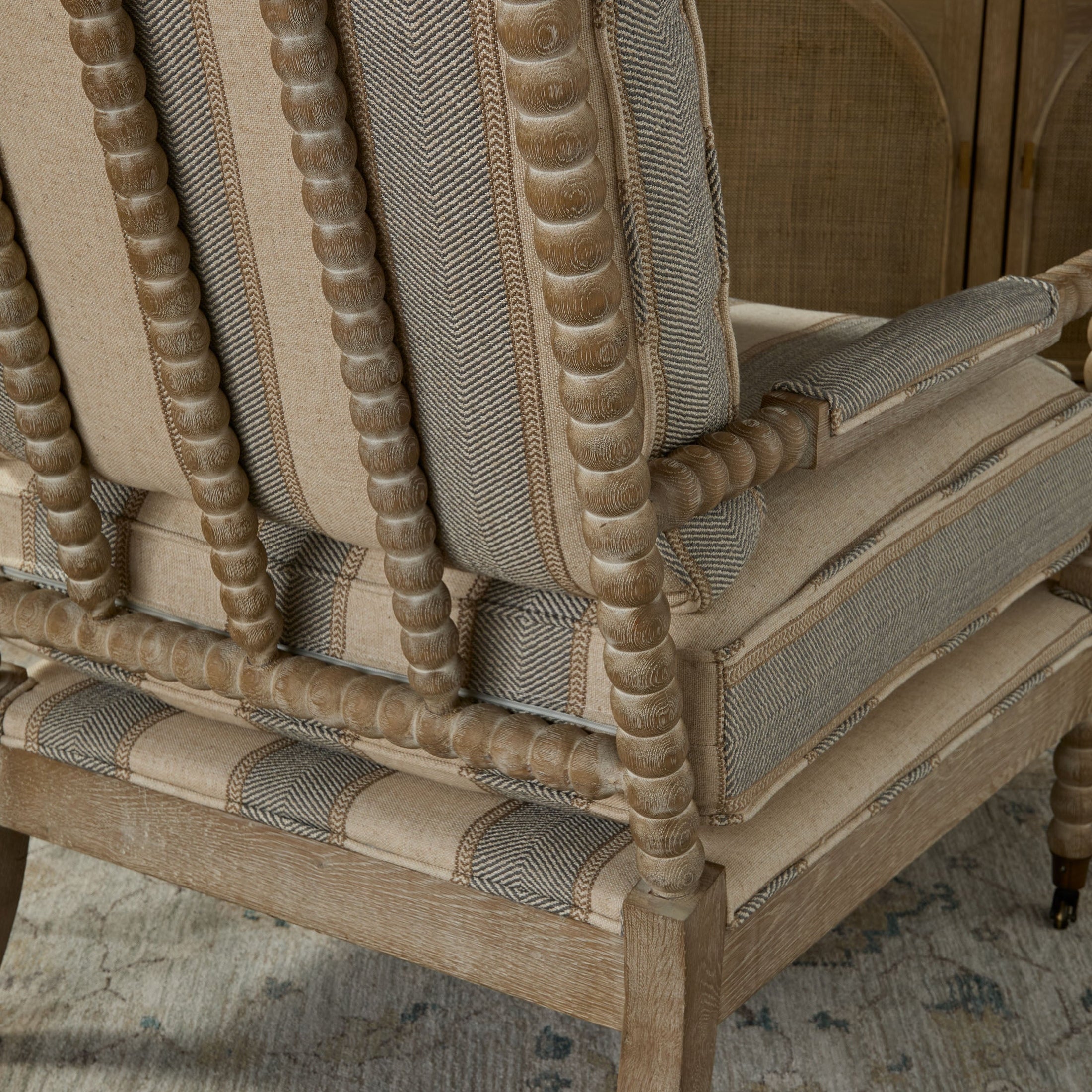 Back view of Rouleau Club Chair by Essentials For Living showing hand-carved spool wood frame and striped upholstery.
