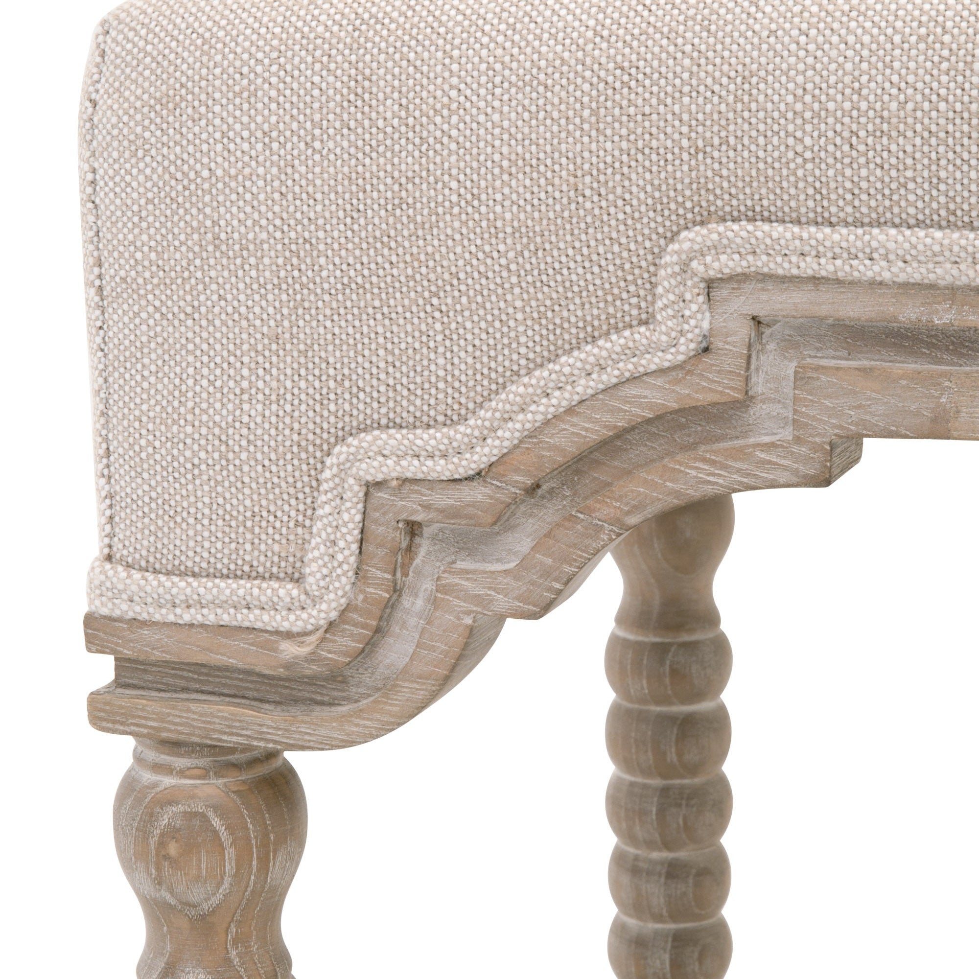 Close-up of Rue Counter Stool showing bisque linen upholstery with double welt trim and carved natural gray ash wood frame
