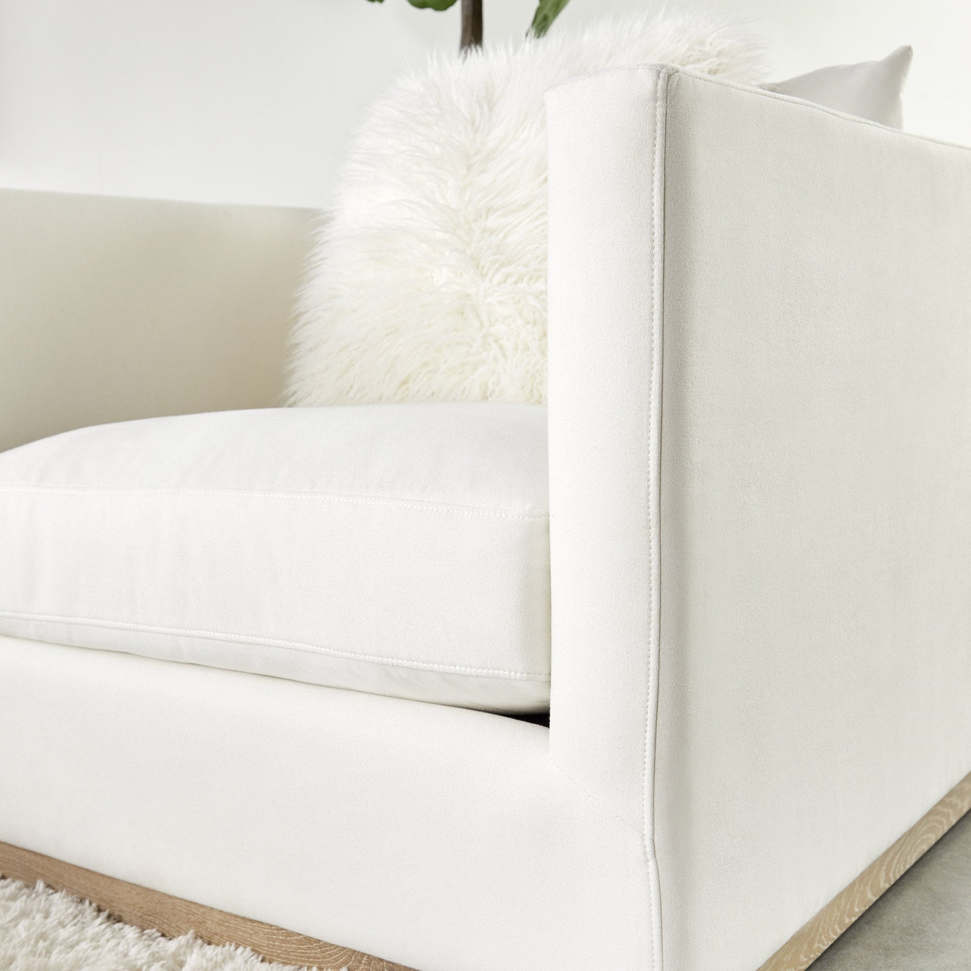 Close-up of Essentials For Living Siena Plinth Base Sofa Chair with ivory upholstery and natural gray oak base