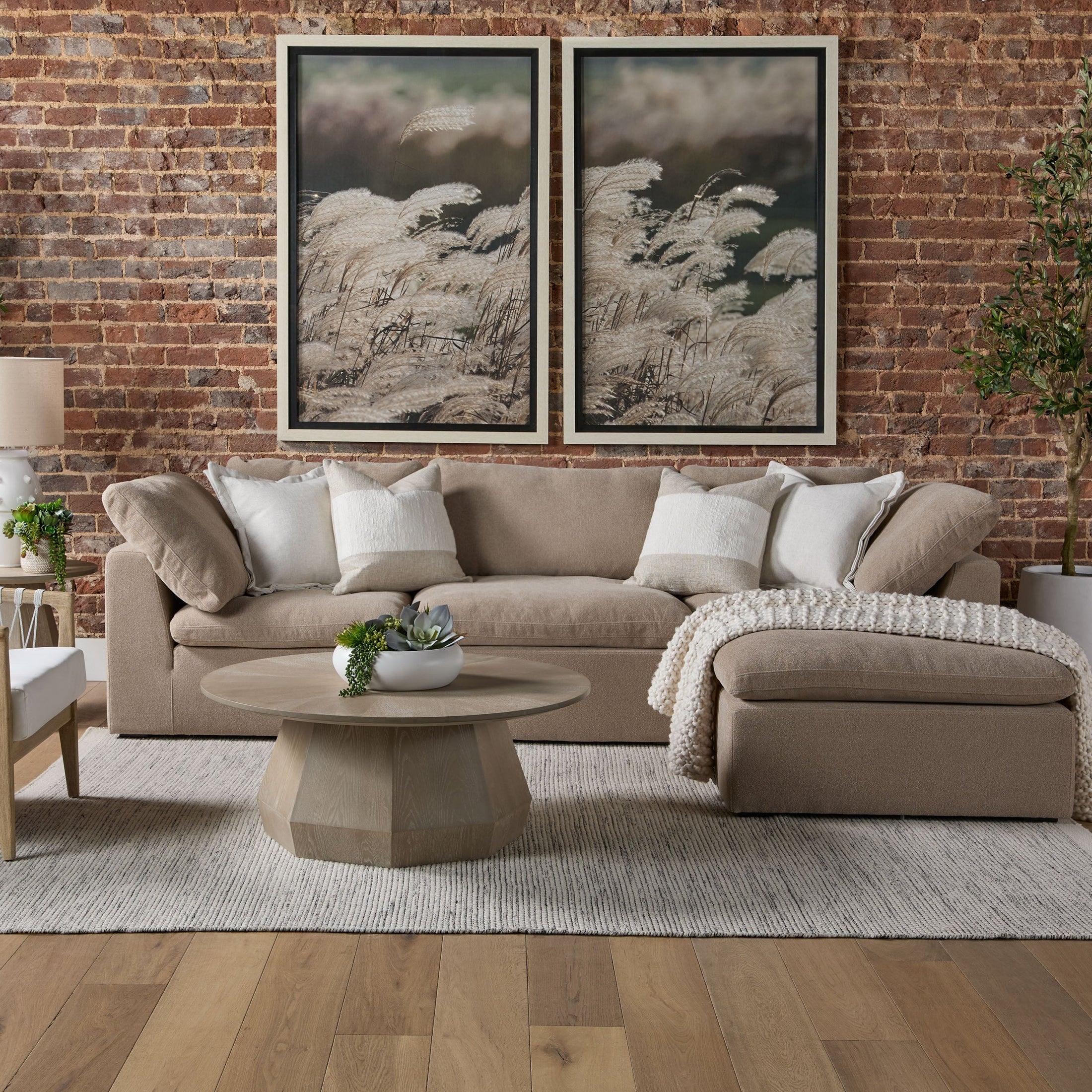 Beige modular sofa with plush cushions and neutral decor, set against an exposed brick wall in a modern living room