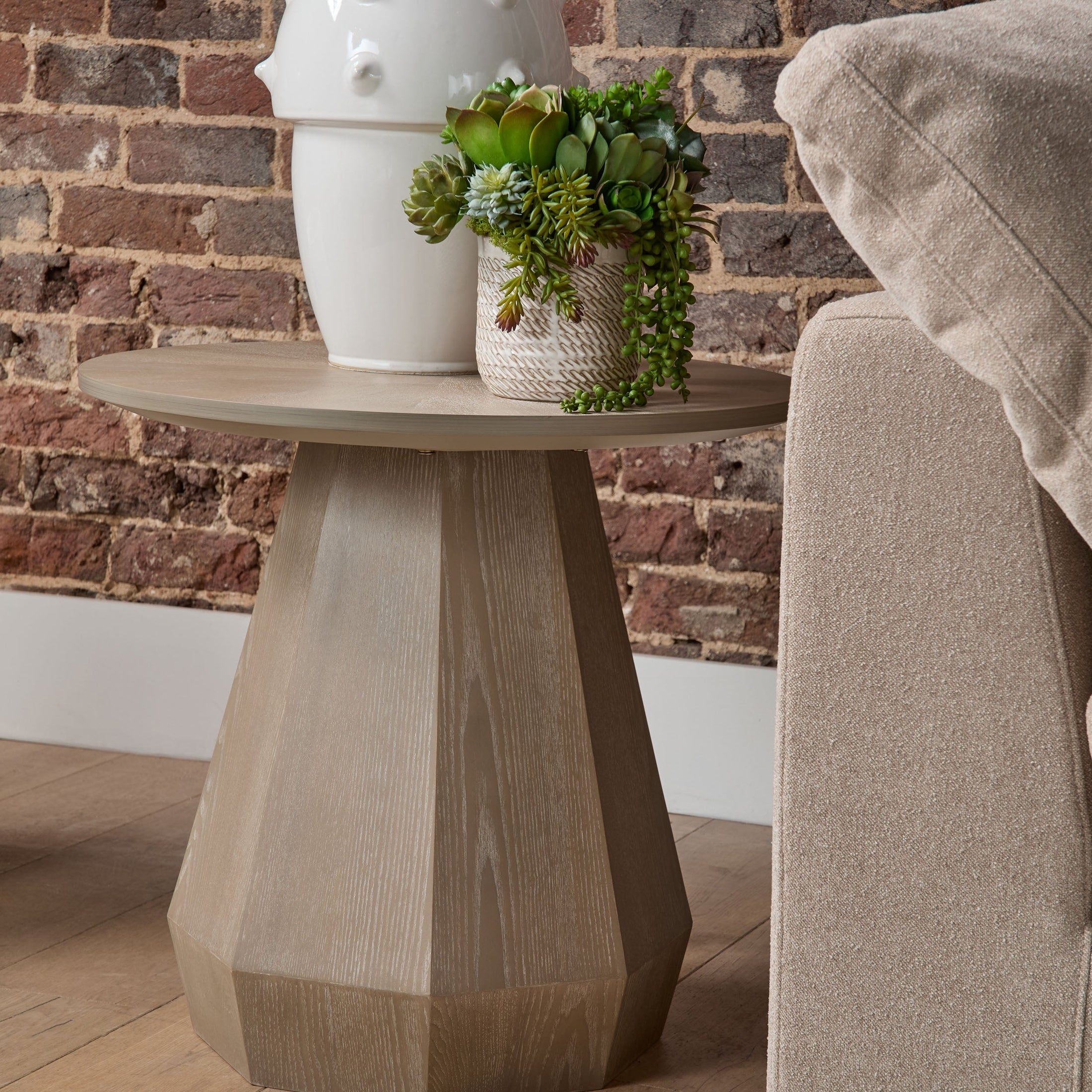 Close-up of a beige Sky Modular Corner Chair next to a geometric wooden side table with plants and decor