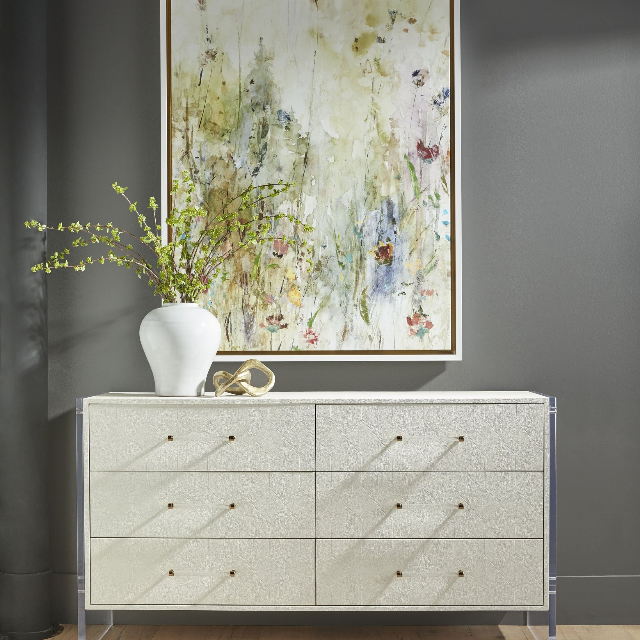 Pearl-white Sonia Shagreen 6-drawer dresser with acrylic legs, brushed brass accents by Essentials For Living in modern room setting.