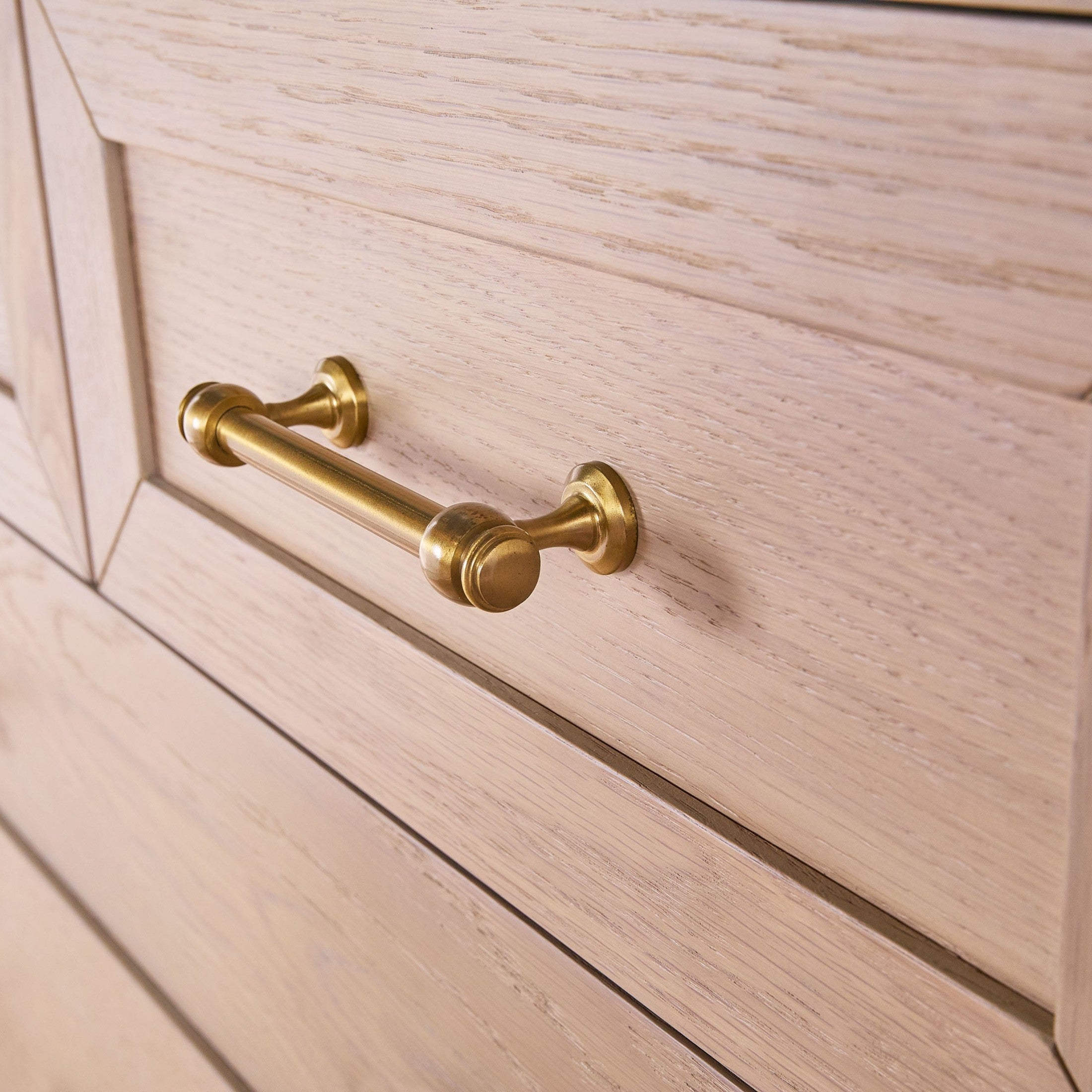 Close-up of brushed brass drawer handle on matte white lacquered wood drawer from Essentials for Living chest