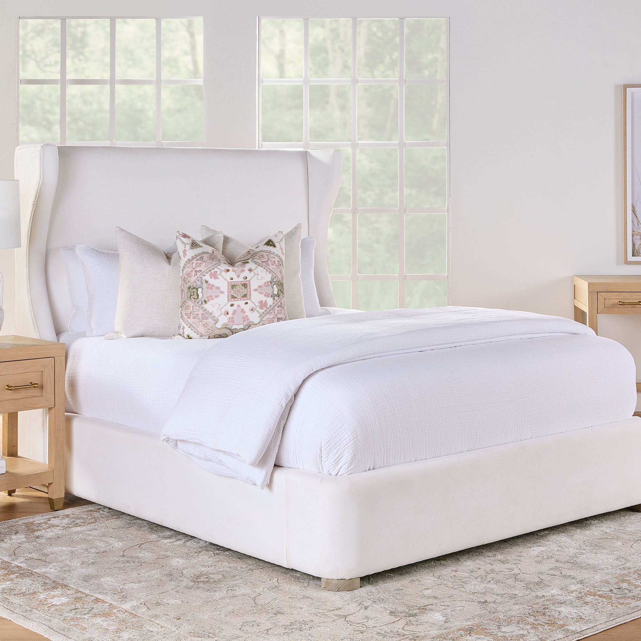 Essentials For Living Stella 1-Drawer Nightstand in matte white lacquer with brass hardware and lower shelf in a bright bedroom setting