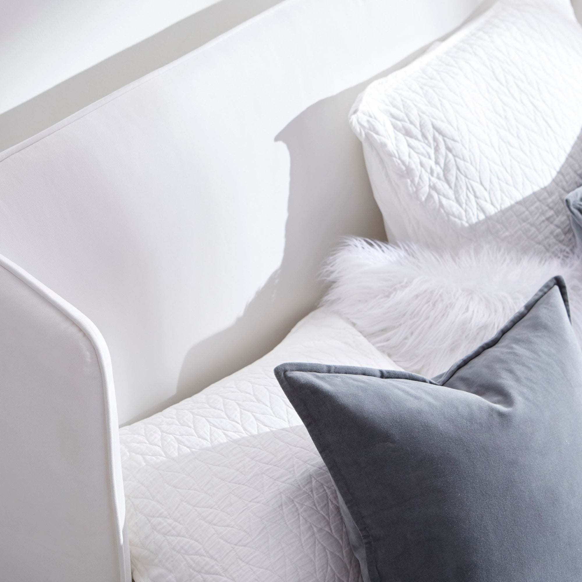 Close-up of white quilted mattress on Stewart Standard King Bed with soft gray and white pillows in natural light