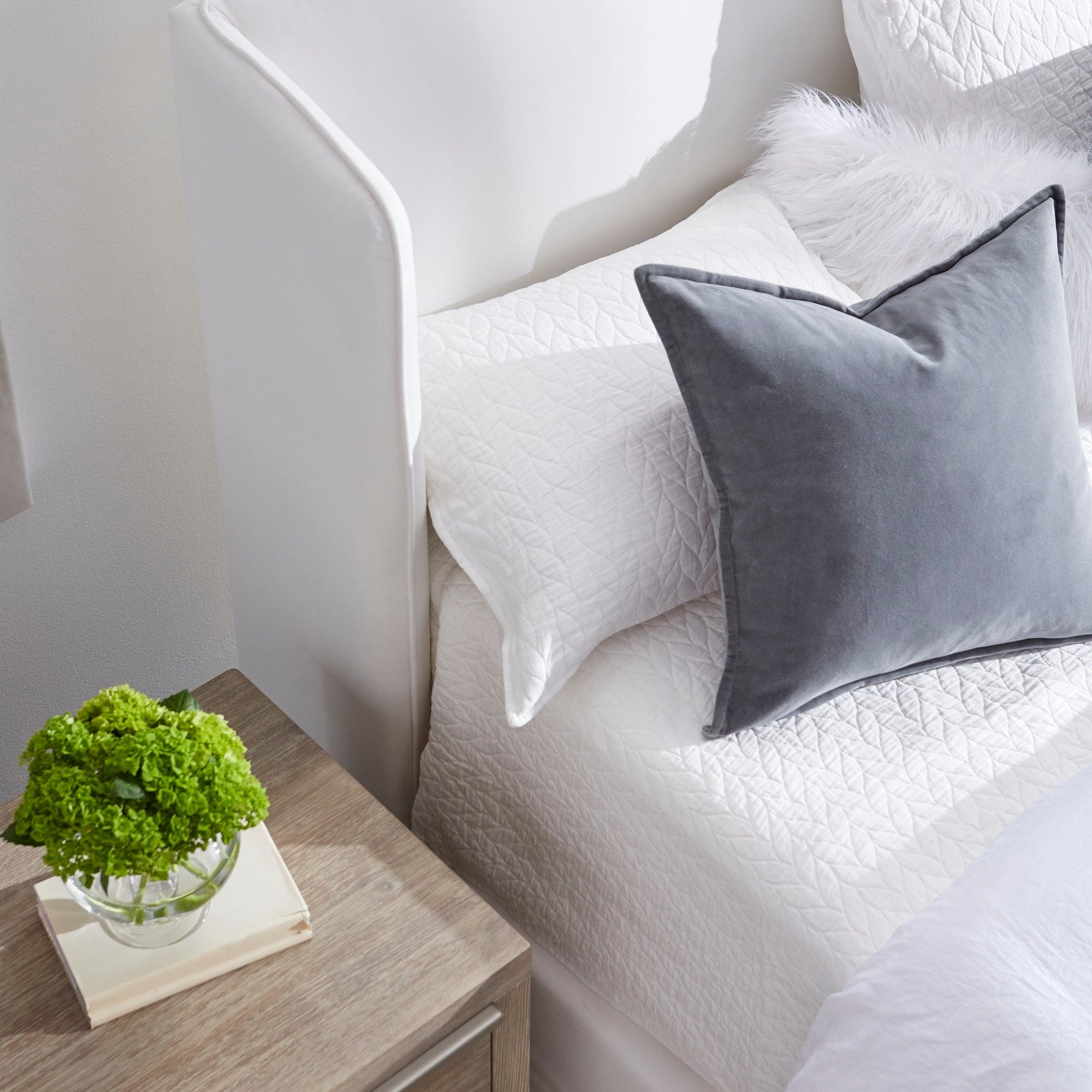 Close-up of Stewart Queen Bed wingback headboard with white bedding and gray accent pillow in natural light