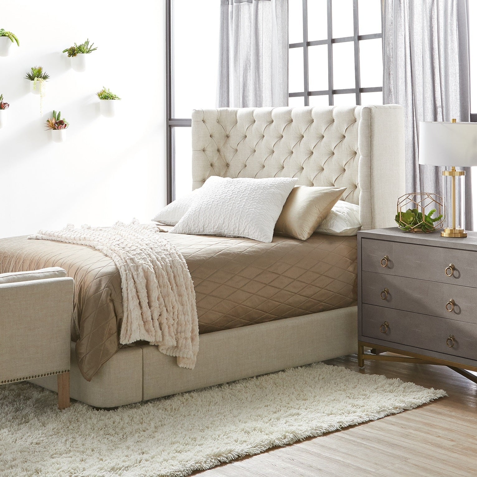 Strand Shagreen 3-drawer nightstand in pearl white faux shagreen with brushed gold pulls beside a beige upholstered bed.