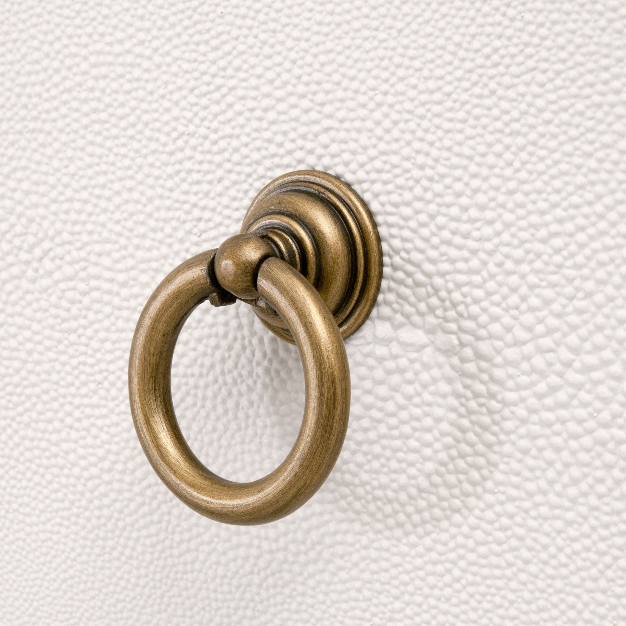Close-up of brushed gold ring pull handle on gray faux shagreen textured surface of Essentials For Living nightstand drawer