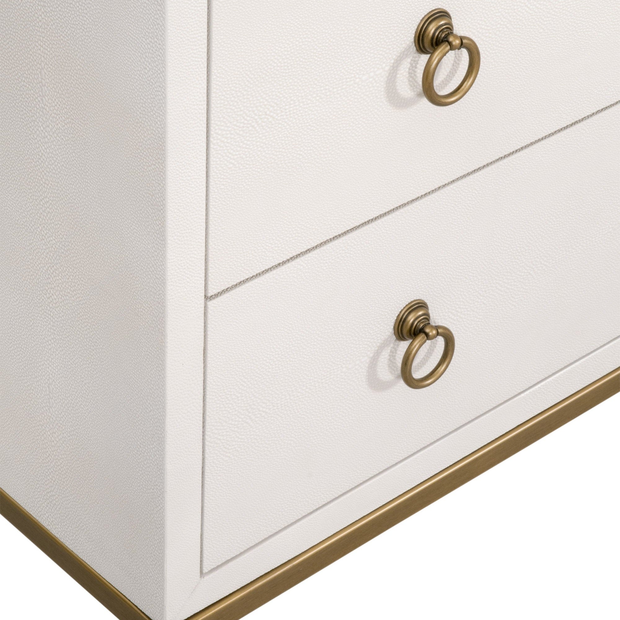 Close-up of pearl white faux shagreen dresser drawers with brushed gold ring pulls and modern gold base accents