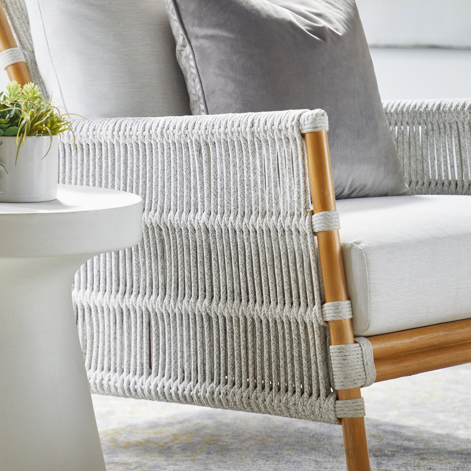Ivory nano-sealed concrete Tack Accent Table beside woven rope and wood framed outdoor chair with cushions