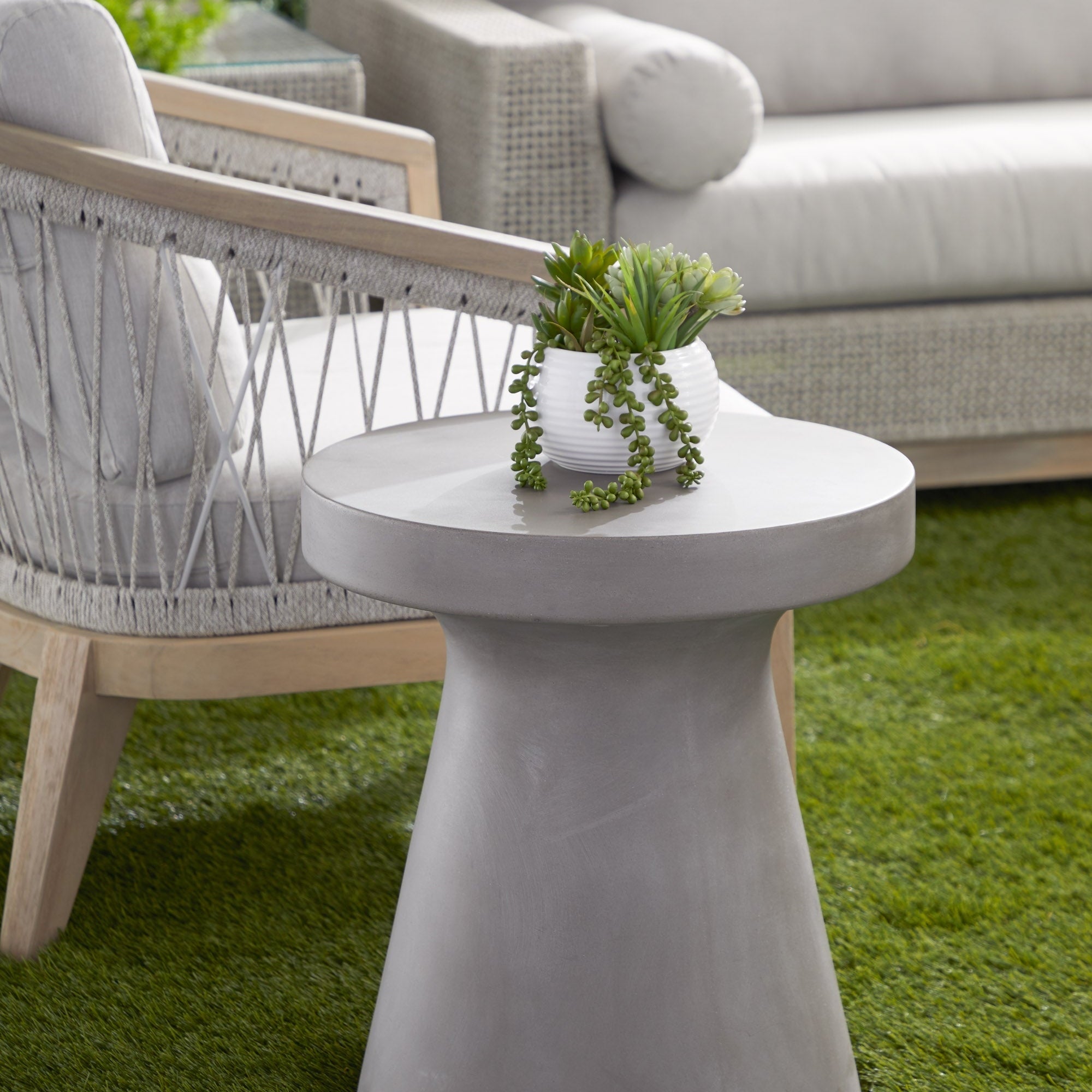 Essentials for Living Tack Accent Table in ivory fiber-reinforced concrete with decorative plant on top in outdoor setting