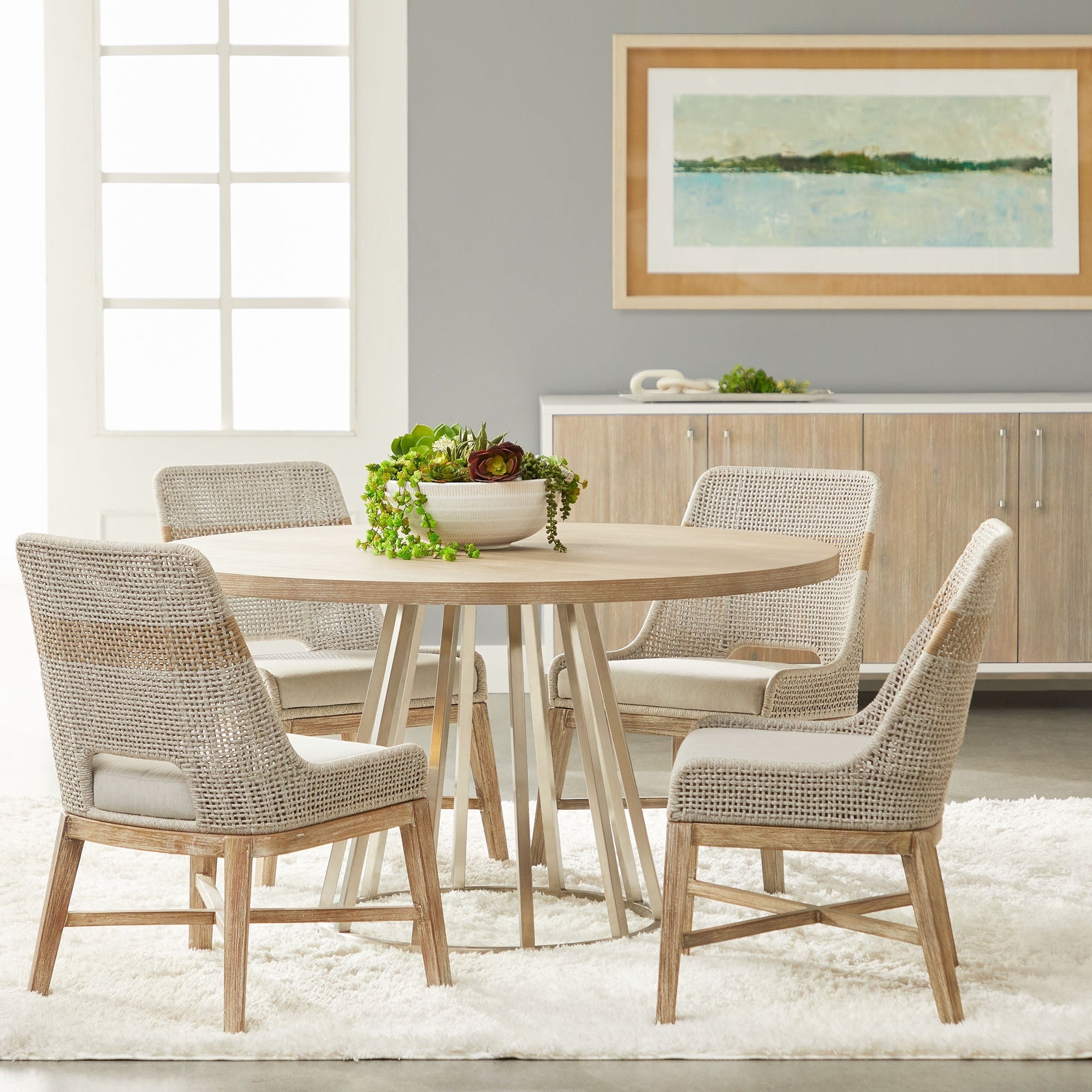 Set of four coastal style dining chairs with woven taupe and white rope backs and wooden legs around round table