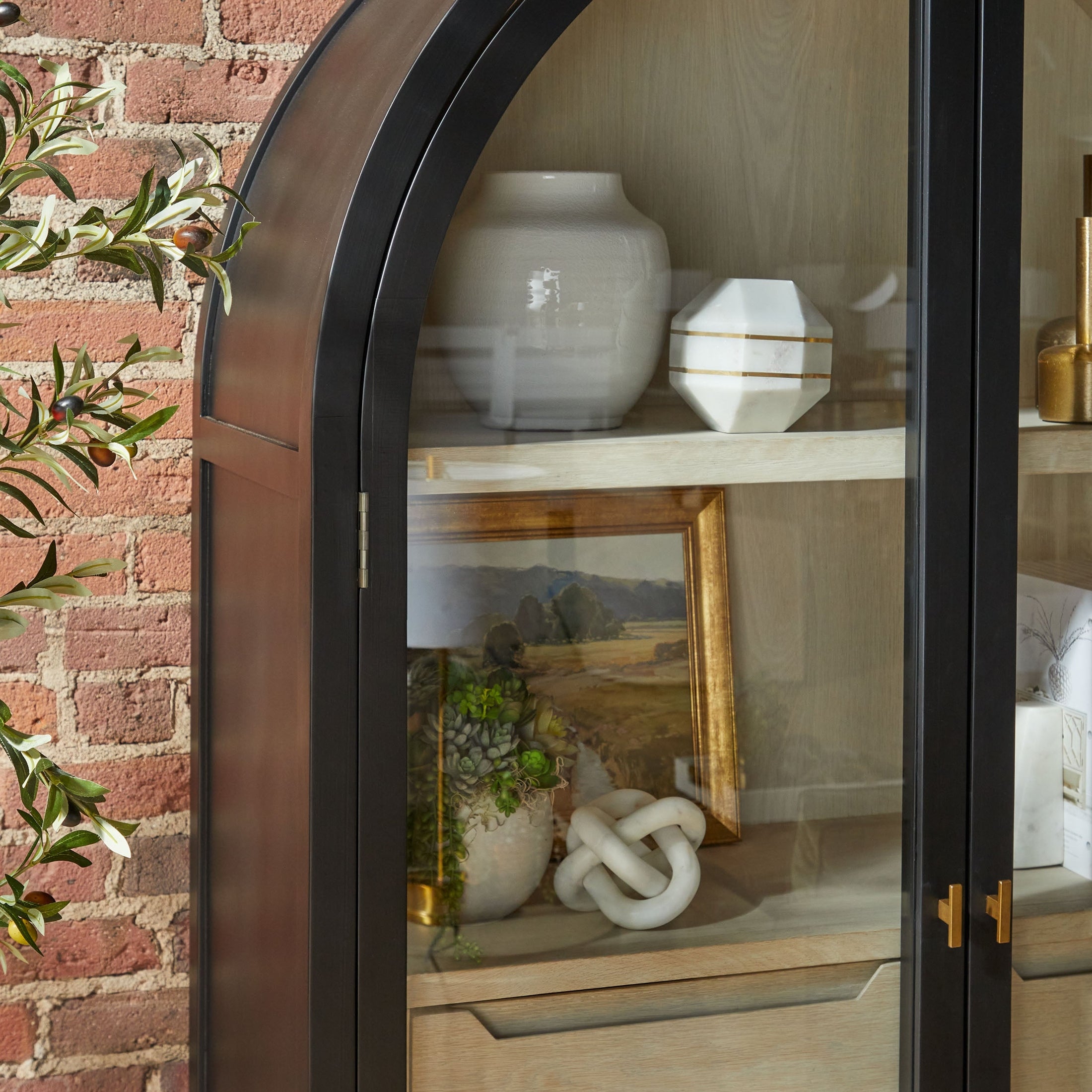 Essentials for Living Toulouse Display Cabinet with black birch frame, natural oak interior, glass doors, and gold hardware.